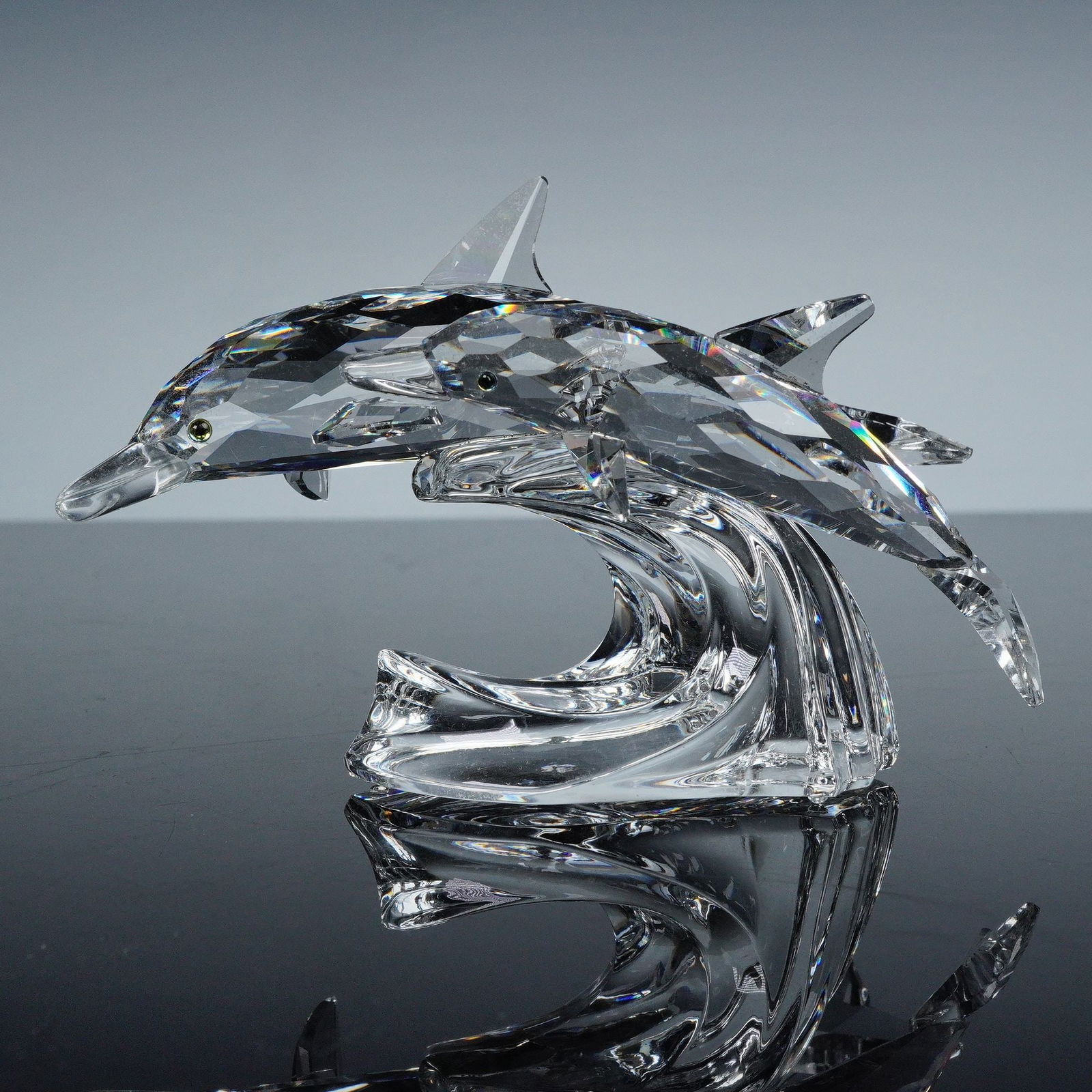 Swarovski Crystal Figurine, Lead Me Dolphins: A finely faceted crystal figure that was the second SCS trilogy part of the Mother and Child collection. The Dolphins are made from clear crystal and they are swimming on top of a clear crystal wave.