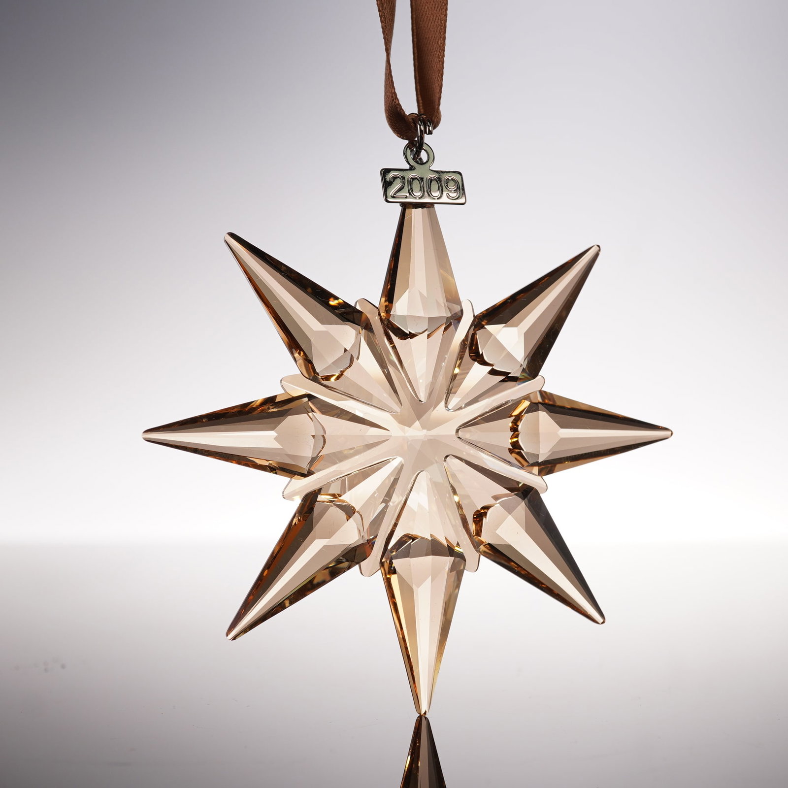 Swarovski Crystal Ornament, 2009 Christmas Gold: Swarovski 2009 Christmas Ornament Gold SCS 1026761 crafted in faceted golden crystal with multi point star design and hanging ribbon, features Swarovski backstamp, includes original box 5.5"H. Artist: