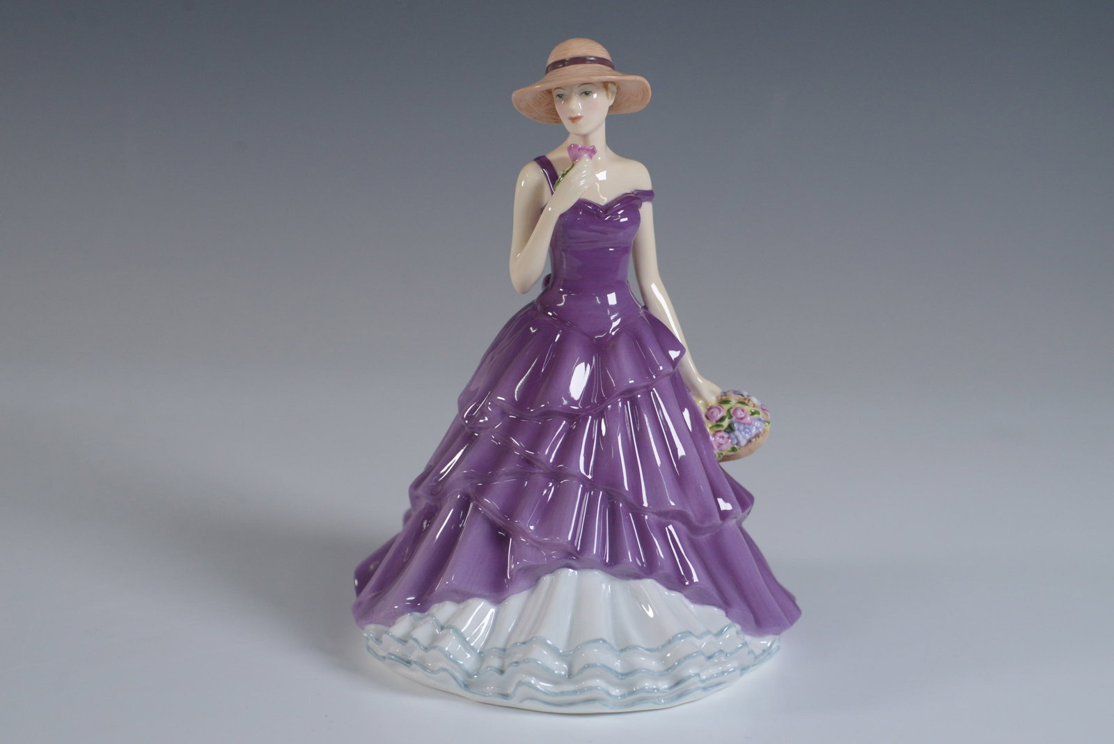 Royal Doulton Pretty Ladies Figurine, Megan HN5512: A Royal Doulton Pretty Ladies figurine titled Megan, model HN5512. This elegant hand-decorated fine bone china figurine features a woman in a flowing purple gown with a layered ruffle design, a delica