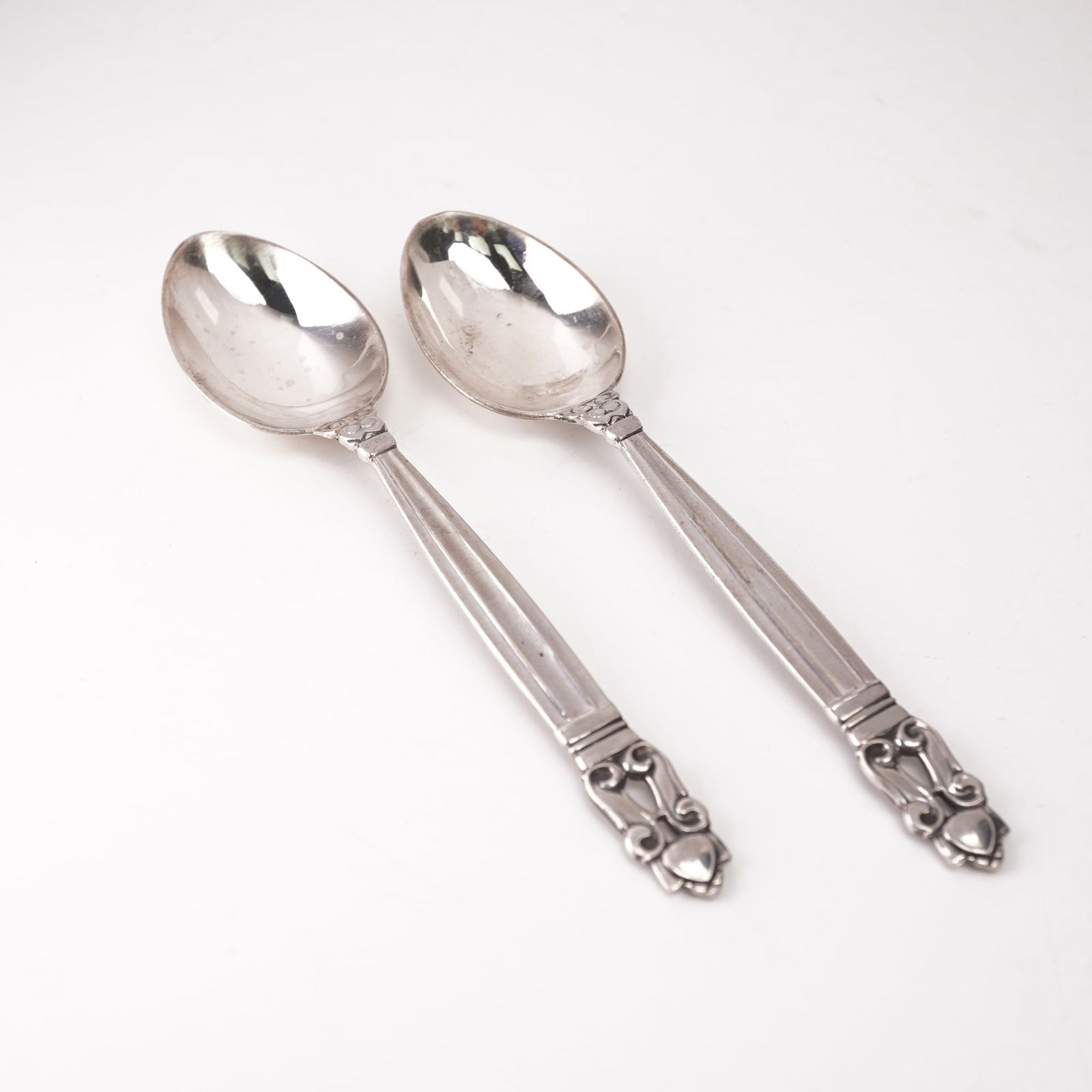 2pc Georg Jensen Sterling Silver Fruit Spoons, Acorn: Pair of Georg Jensen sterling silver fruit spoons in the Acorn pattern, designed by Johan Rohde and introduced in 1915. Each spoon features a gently rounded bowl and a tapered handle with fluted lines