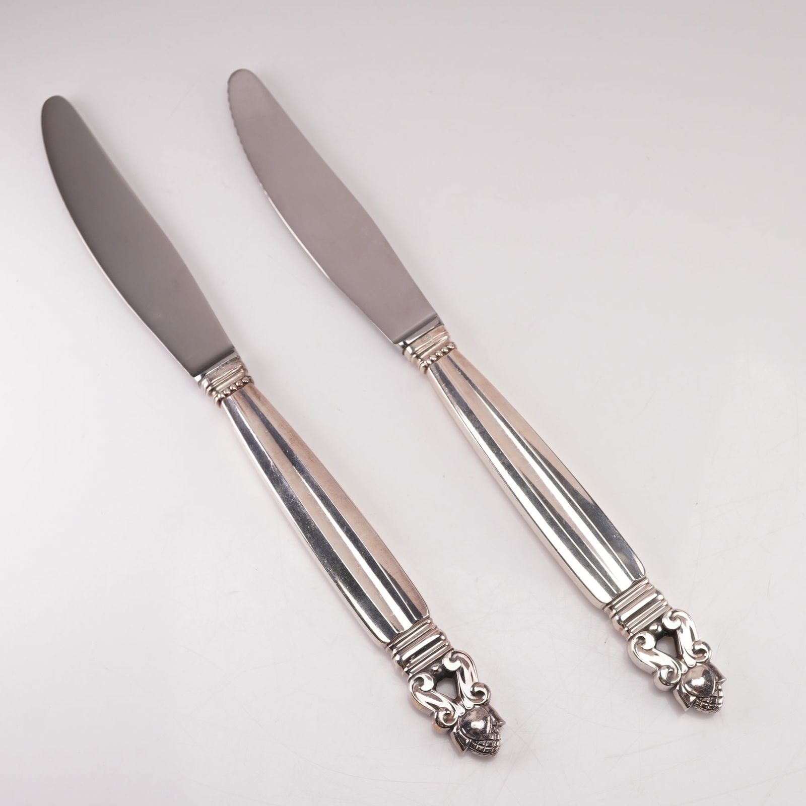 2pc Georg Jensen Sterling Silver Stainless Steel Dinner Knives, Acorn: A two-piece lot of Georg Jensen dinner knives in the Acorn pattern, designed by Johan Rohde in 1915. Each knife features a sterling silver handle marked Sterling Denmark with the Georg Jensen hallmark