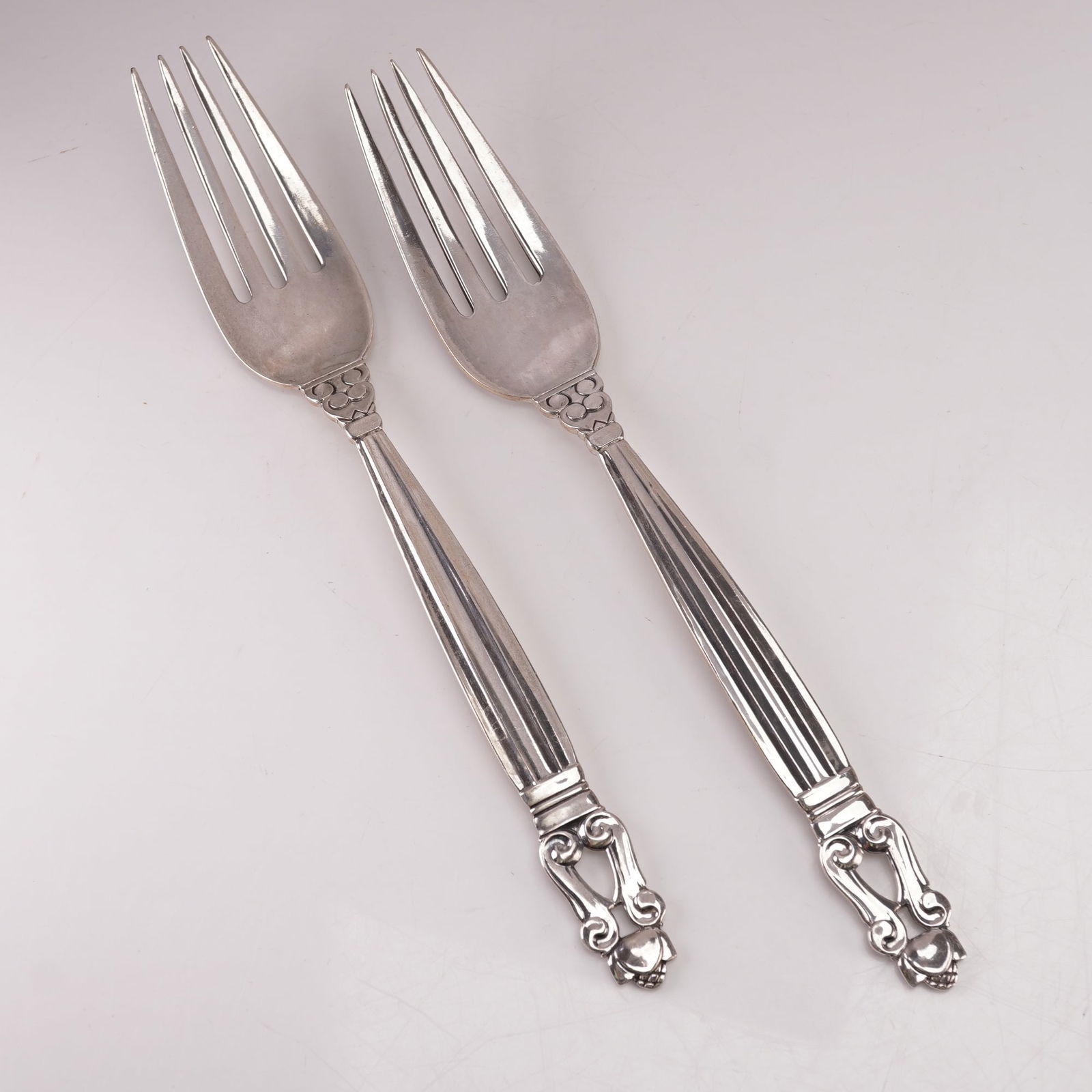 2pc Georg Jensen Sterling Silver Dinner Forks, Acorn: A two-piece set of Georg Jensen sterling silver dinner forks in the Acorn pattern, designed by Johan Rohde in 1915. Each marked Georg Jensen Sterling Denmark. The pattern features a fluted handle with