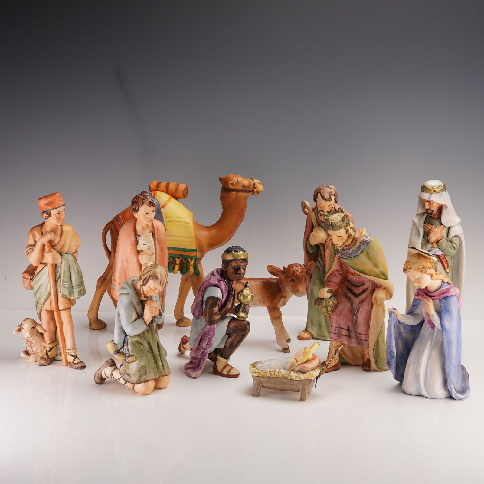 11pc Goebel Hummel Hand Painted Nativity Figurines: The set includes Mary, Joseph, the Baby Jesus in a manger, three Wise Men bearing gifts, two shepherds-one kneeling with a lamb-along with a camel and a cow to complete the traditional scene. Each fig