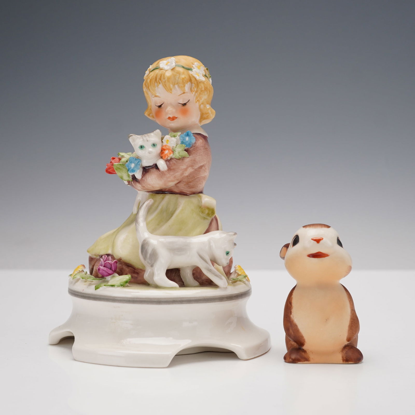 2pc Goebel Porcelain Girl and Animals Figurines: Charming group of two Goebel porcelain figurines including a young girl holding a kitten with another cat at her feet, and a small brown and white rabbit figure. Each piece is hand-painted in soft pas