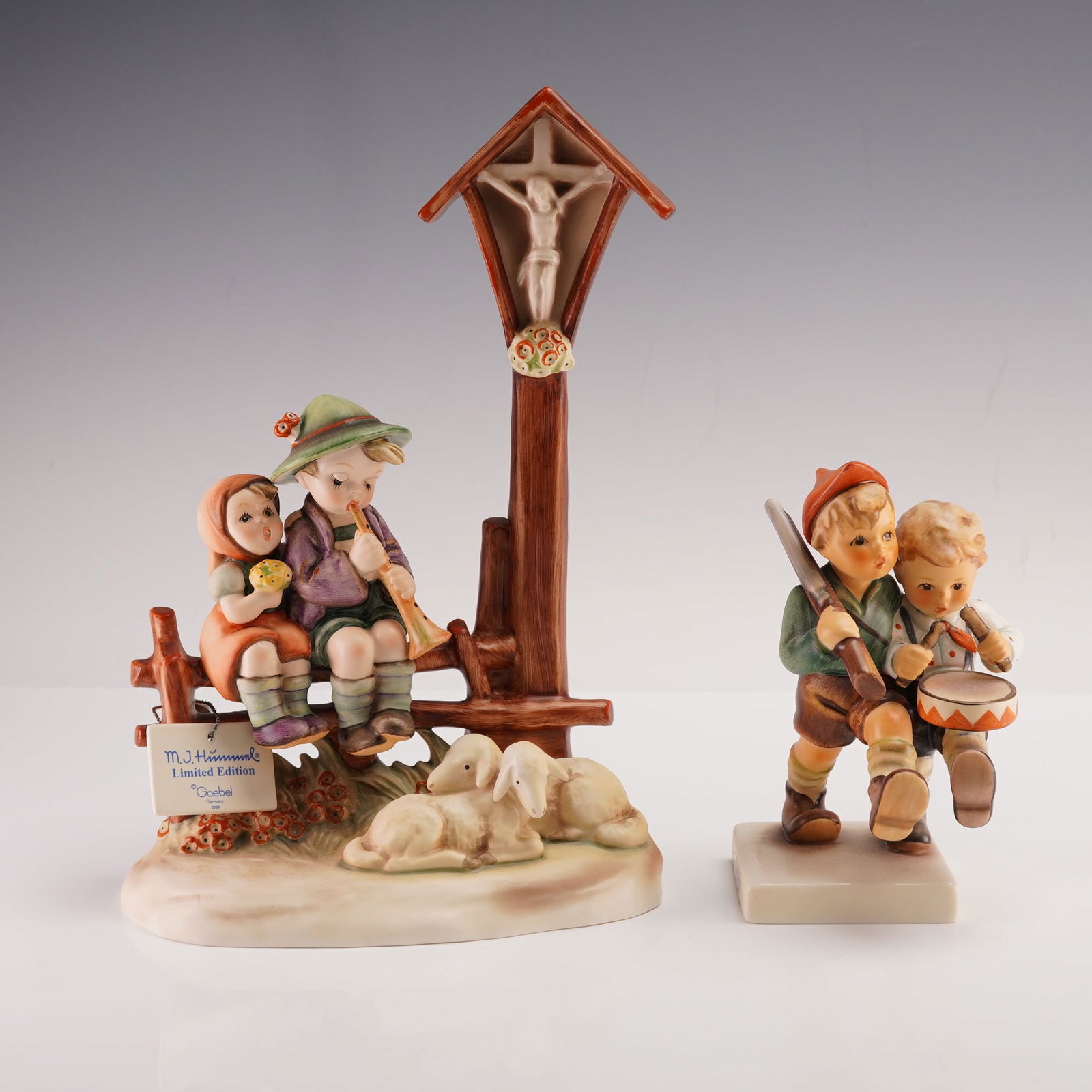 2pc Goebel Hummel Figurines, Volunteers and Wayside Devotion: This pair of Goebel Hummel figurines includes Volunteers and Wayside Devotion. Volunteers shows two boys walking side by side, one carrying a rifle and the other holding a drum while they share a frie