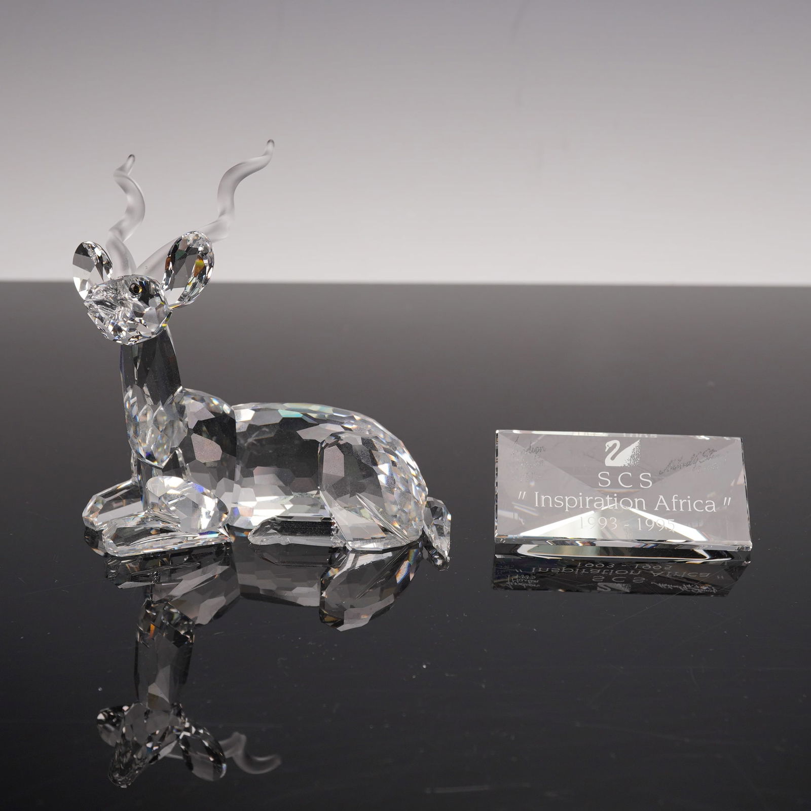 2pc Swarovski Crystal 1994 AE Kudu Figurine + Plaque, Signed: Refined Swarovski Crystal Society (SCS) 1994 Annual Edition figurine, titled Kudu, designed by Michael Stamey as part of the Inspiration Africa trilogy (1993-1995). The graceful antelope is rendered i