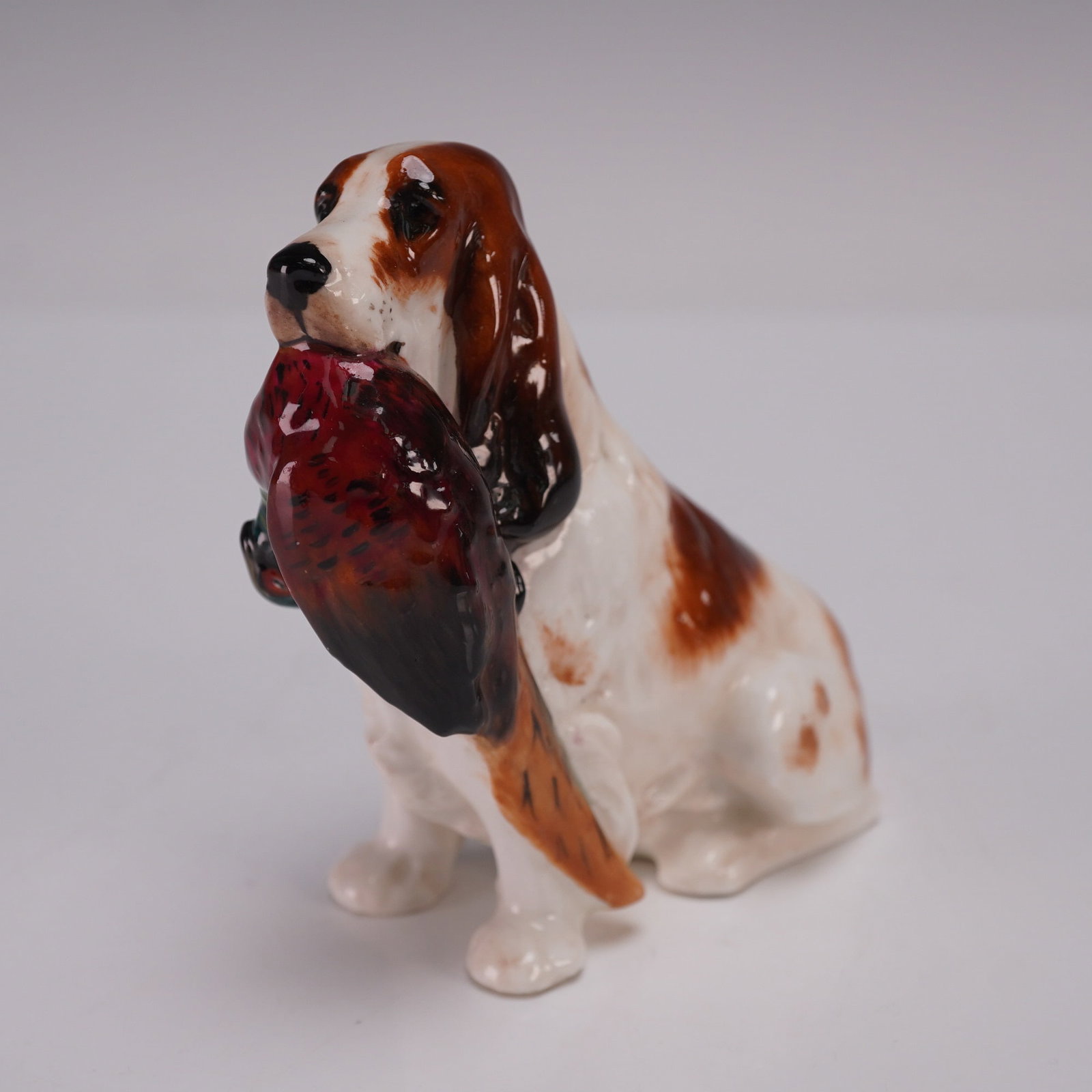 Royal Doulton Figurine, Cocker Spaniel with Pheasant HN1029: A finely hand painted Bone China figurine depicting a seated spaniel with a pheasant held carefully in its mouth, rendered in naturalistic tones of brown, white, and russet with vibrant plumage detail