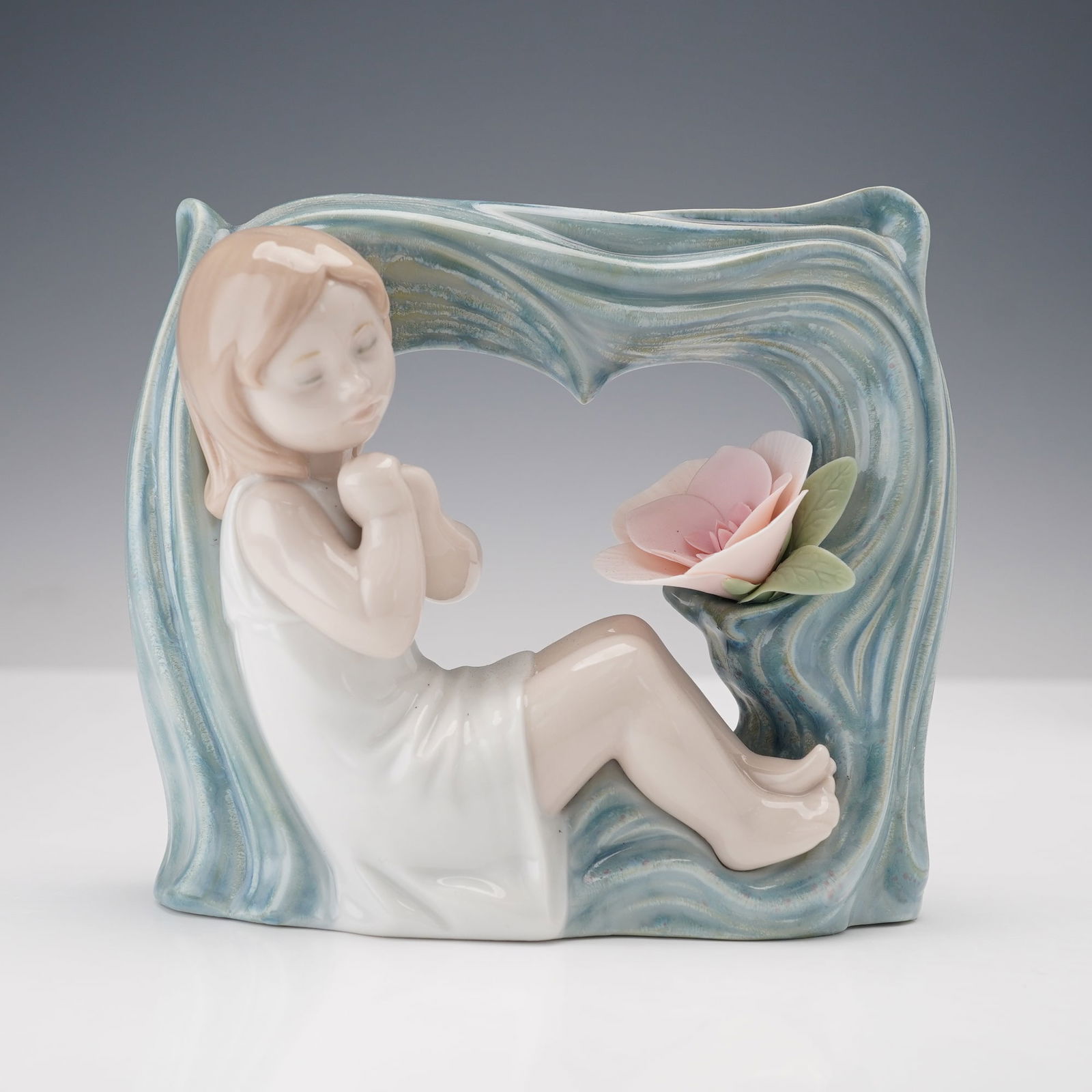Lladro Porcelain Figurine Childhood Fantasy 1008130: This Lladro porcelain figurine, model number 8130, titled Childhood Fantasy, depicts a young girl seated next to a flower. The entire piece, crafted in soft pastel tones, has a glossy finish, while th