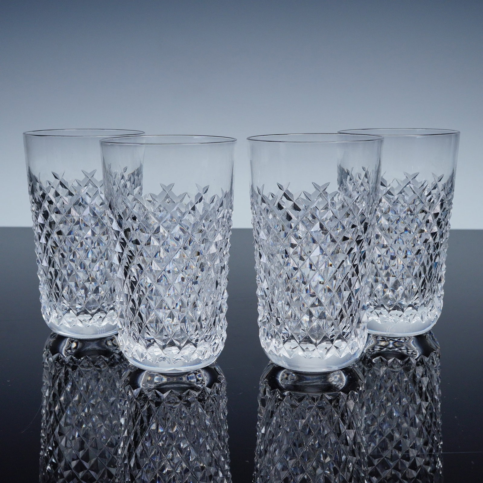 4pc Waterford Alana Crystal Highball Glasses: Showcasing the iconic diamond cut pattern that captures and reflects the light with brilliant clarity. Each glass is finely crafted in heavy lead crystal, designed with straight sides and a slightly r