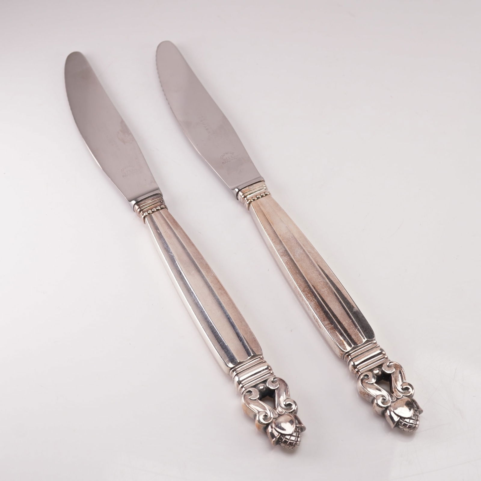 2pc Georg Jensen Sterling Silver Stainless Steel Dinner Knives, Acorn: A two-piece lot of Georg Jensen dinner knives in the Acorn pattern, designed by Johan Rohde in 1915. Each knife features a sterling silver handle marked Sterling Denmark with the Georg Jensen hallmark