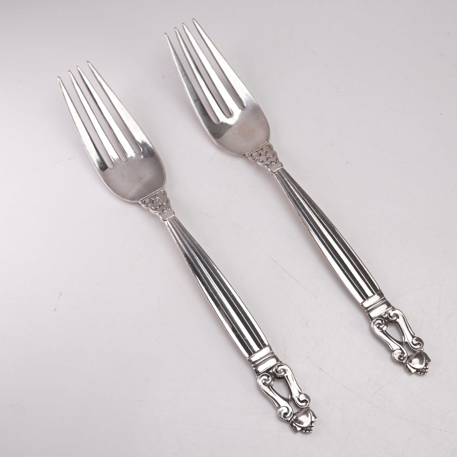 2pc Georg Jensen Sterling Silver Dinner Forks, Acorn: A two-piece set of Georg Jensen sterling silver dinner forks in the Acorn pattern, designed by Johan Rohde in 1915. Each marked Georg Jensen Sterling Denmark. The pattern features a fluted handle with