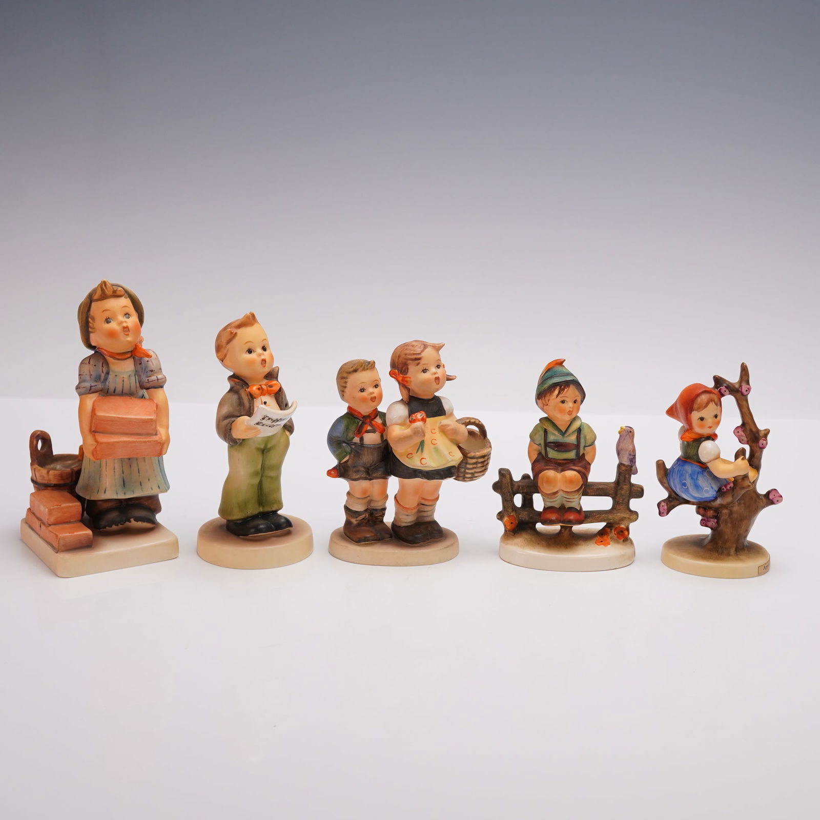 5pc Goebel Hummel Childhood Figurines: Five porcelain figurines depicting charming childhood scenes. Includes The Builder (305) featuring a girl carrying bricks, Soloist (135) with a boy singing from sheet music, To Market (49/I) showing a