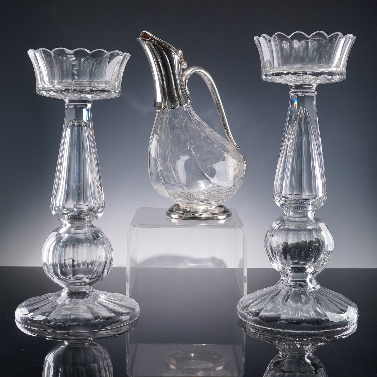 3pc Clear Glass and Silver Accent Set, Pitcher and Candlesticks: A refined three-piece set featuring two tall candlesticks and a matching pitcher, each crafted in clear pressed glass with elegant ribbed detailing and scalloped forms. The candlesticks feature a flut