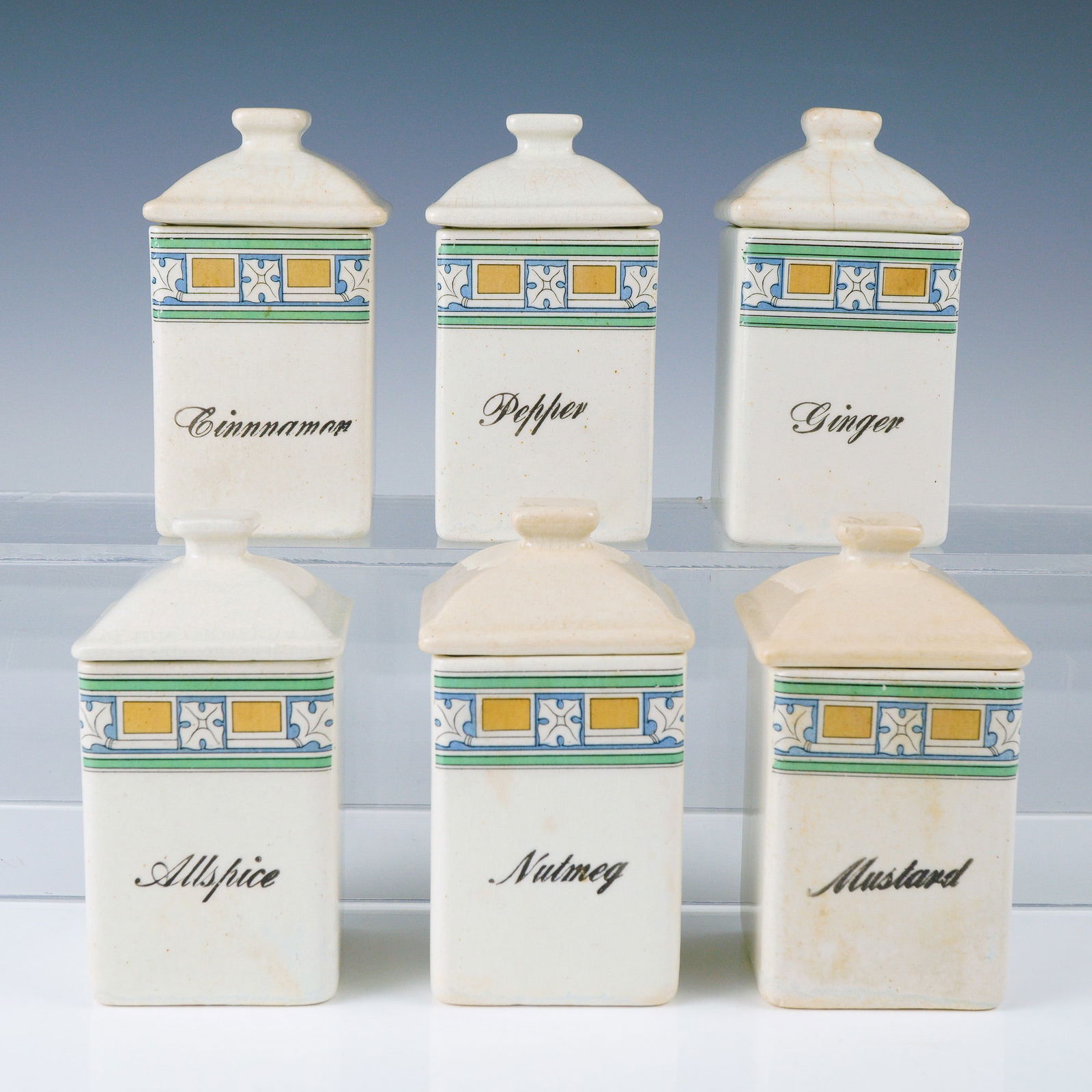 Ceramic Kitchen Canisters, Spices: This charming set of six antique ceramic spice canisters brings a touch of vintage elegance and functional charm to any kitchen or collector's display. Each canister is finely crafted in a squared, ve