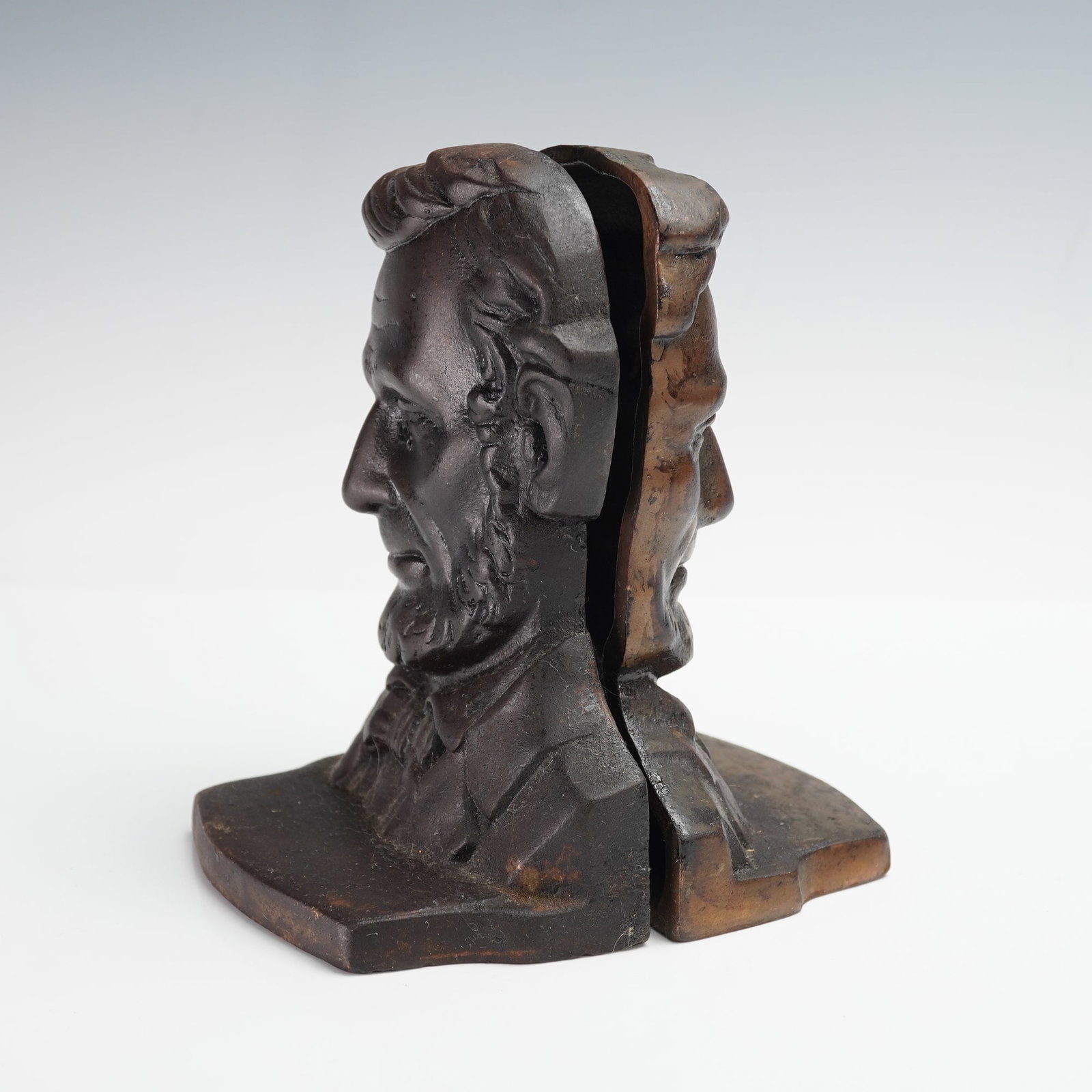 Pair of Cast Bronze Bookends, Abraham Lincoln: A pair of early 20th century cast bronze bookends depicting the profile of Abraham Lincoln, each rendered with fine detail showing his distinctive features and beard. The heavy bronze construction and