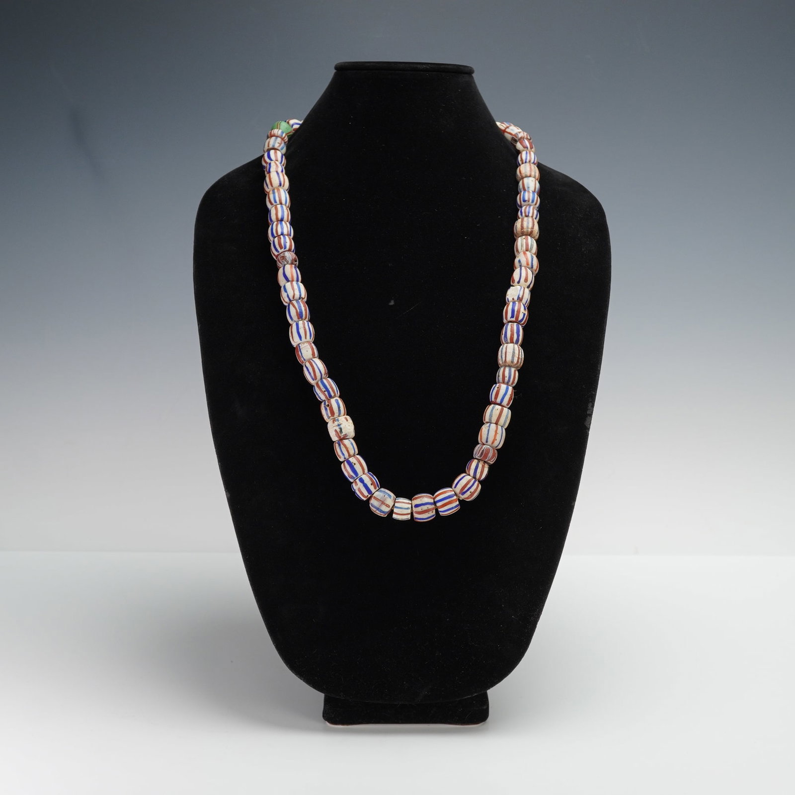 African Red, White, and Blue Trade Bead Necklace: Striking African glass trade bead necklace composed of large powder glass and millefiori-style striped beads in red, white, and blue hues. Each handmade bead displays natural irregularities characteri