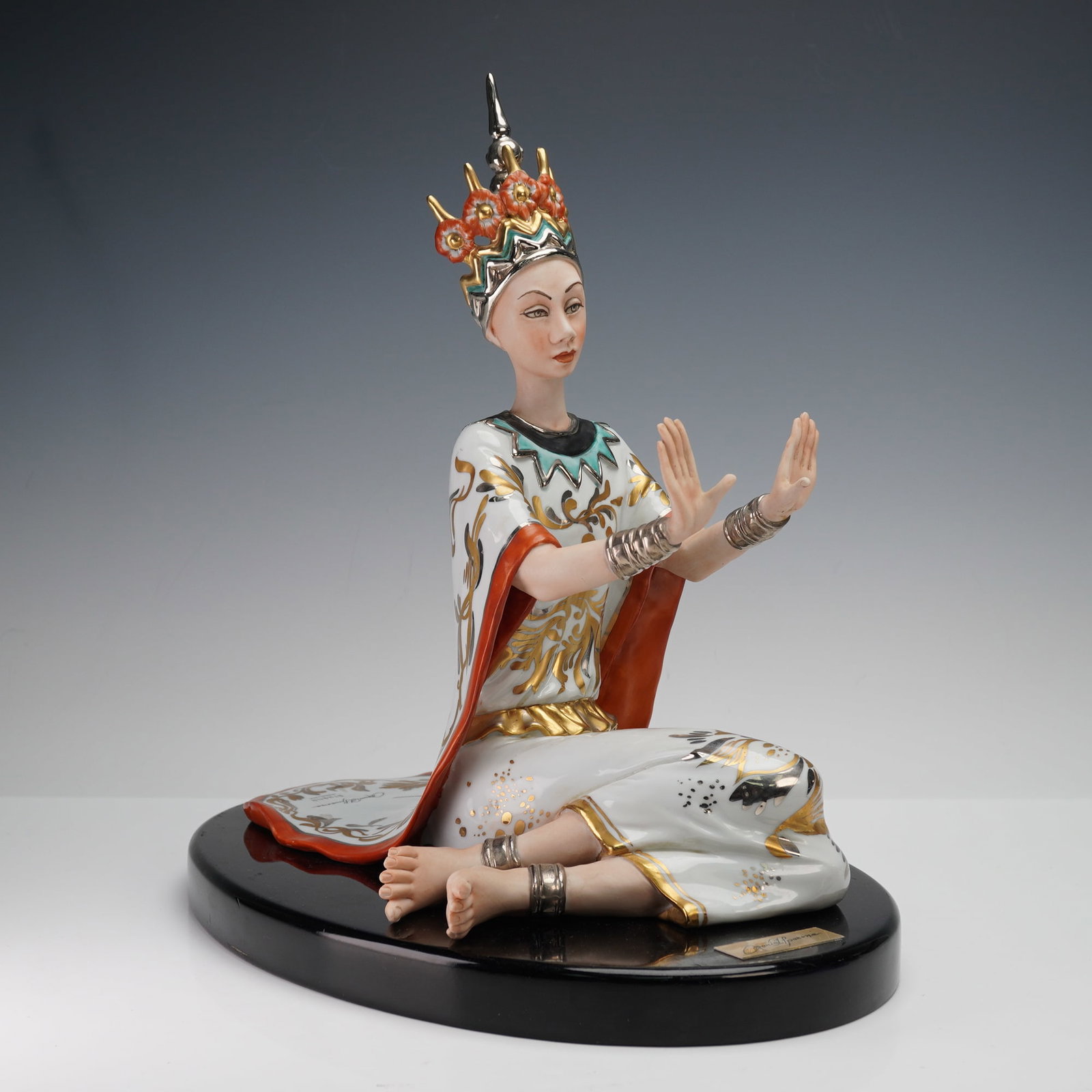 Athena Porcellane Porcelain Figurine Oriental Queen with Base: This exquisite porcelain figurine by Mario Alparone for Athena Porcellane features an Oriental Queen adorned with a detailed floral crown and flowing robes. The figurine showcases beautiful metallic g