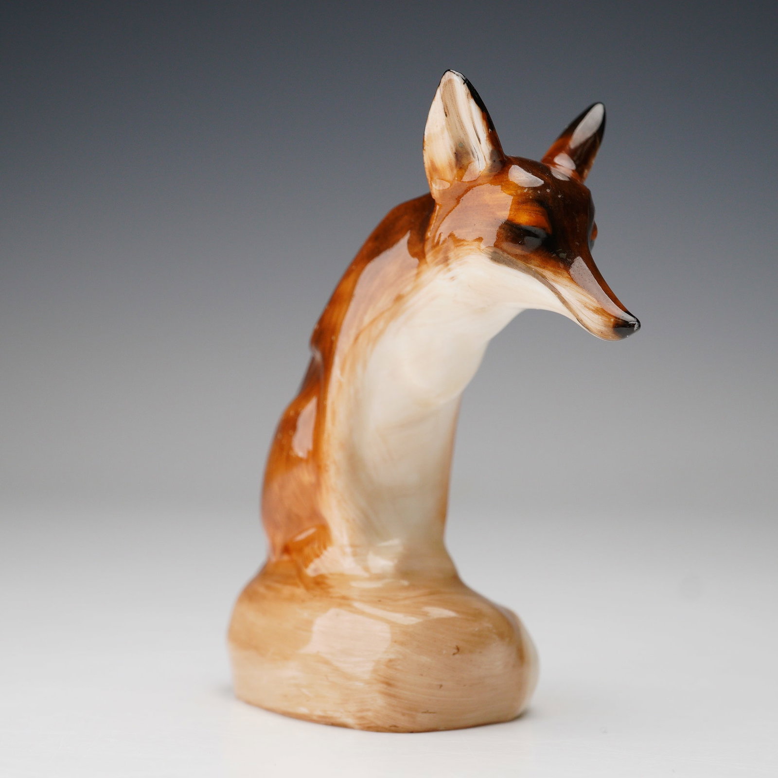 Royal Doulton Animal Figurine, Fox Seated HN147C-1: A finely modeled Royal Doulton porcelain figurine depicting a seated fox with a slender, elegant form and rich brown and cream glaze. The sculpted details capture the animal's alert expression and gra