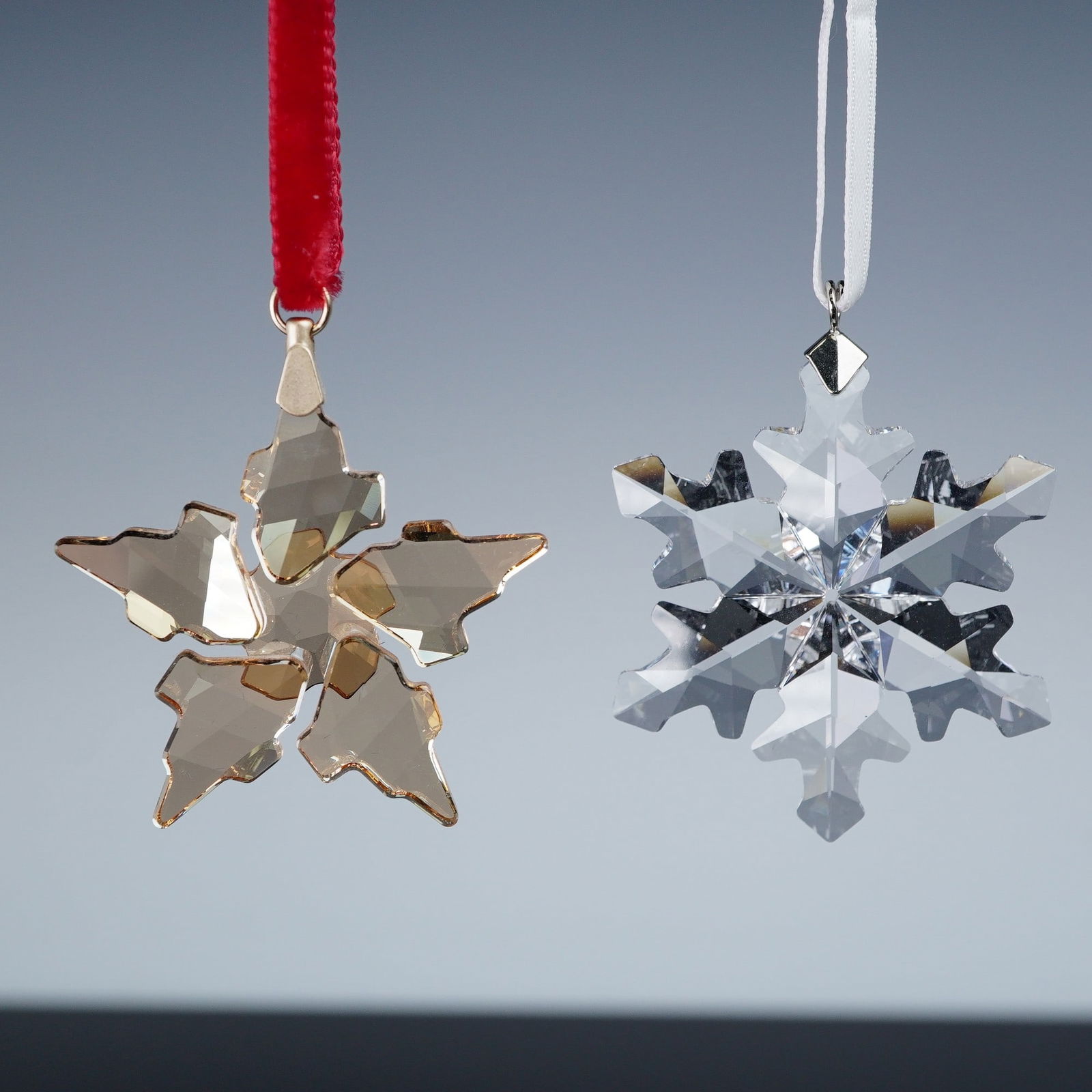 2pc Swarovski Crystal Christmas Ornaments: Pair of Swarovski crystal ornaments. Includes the 2012 Little Snowflake Christmas Ornament, number 1139969, a faceted clear crystal snowflake suspended from a white ribbon. Also features the 2021 Fest