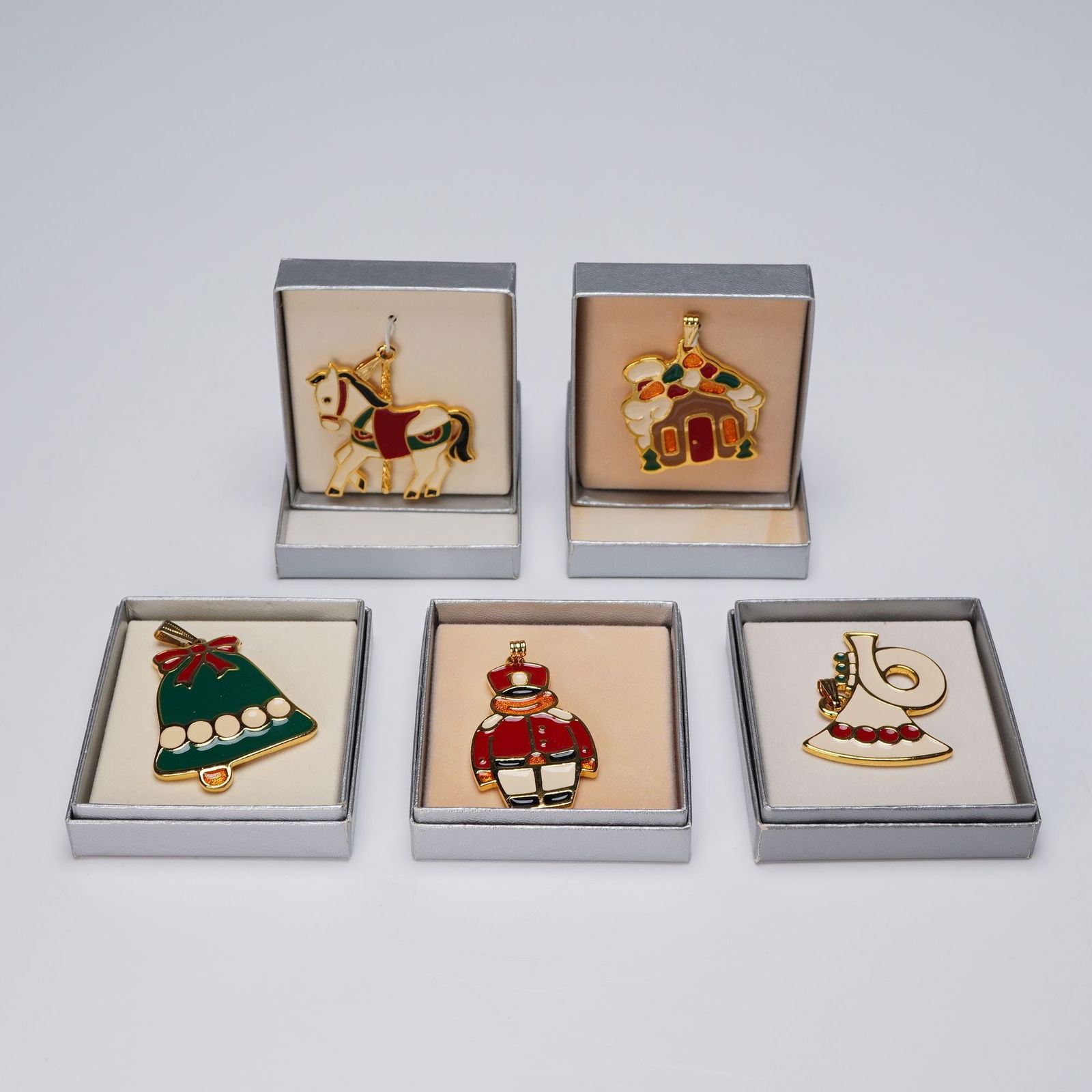 5pc Wallace Silversmiths Enameled Christmas Pendants: A distinguished ensemble of five gold tone Christmas ornaments, each adorned with vibrant hand-painted enamel and finished in a luminous gold tone. This festive assortment includes a French Horn, a Ho