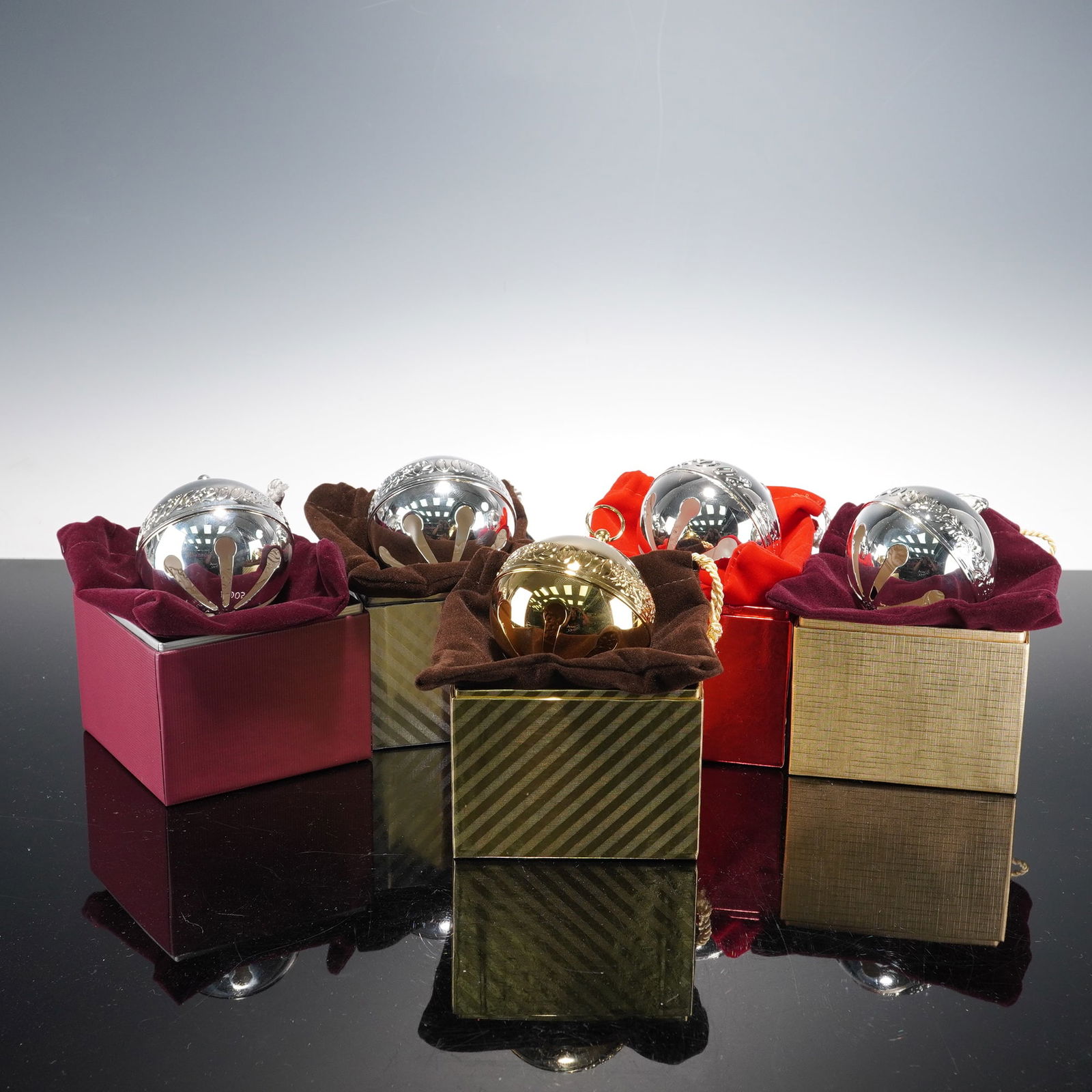 5pc Wallace Silversmith Sleigh Bells: A festive collection of ornamental Christmas bells, each finely crafted with intricate detailing and reflective finishes. The set includes four silver-plated bells and one striking gold-plated example