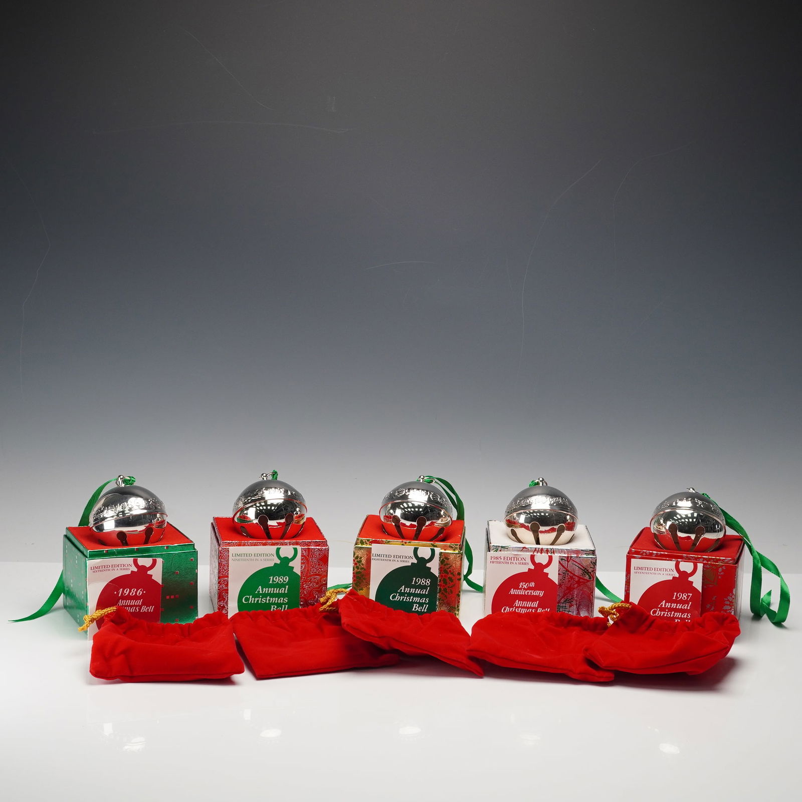 5pc Wallace Silversmiths Annual Christmas Bell Tree Ornaments: This set includes five Wallace Silversmiths Annual Christmas Bell ornaments from 1985 through 1989. Each silver-plated bell has a polished mirrored finish with the year and festive motifs such as Chri