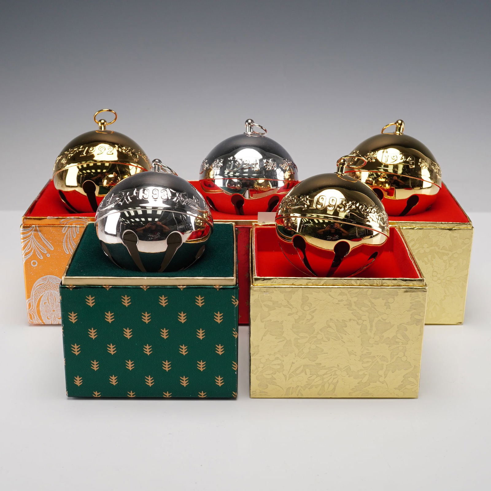 5pc Wallace Silversmiths Annual Sleigh Christmas Bell Ornaments: A set of five Wallace Silversmiths Annual Sleigh Bell ornaments, each crafted in silverplate or gold-tone finish and engraved with the corresponding year. Each presented in its original fitted present