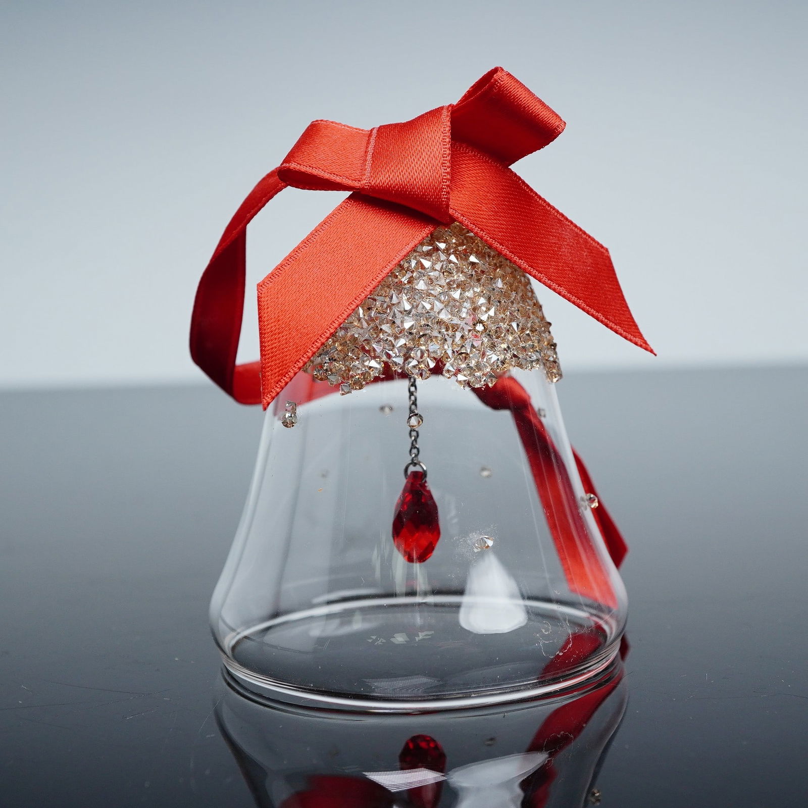 Swarovski Crystal Ornament, Bell Golden Shadow Small: Swarovski crystal Christmas ornament, Bell Golden Shadow Small, item number 5464882. Features a clear crystal bell with golden shadow top, red ribbon, and a suspended red crystal drop. Includes origin