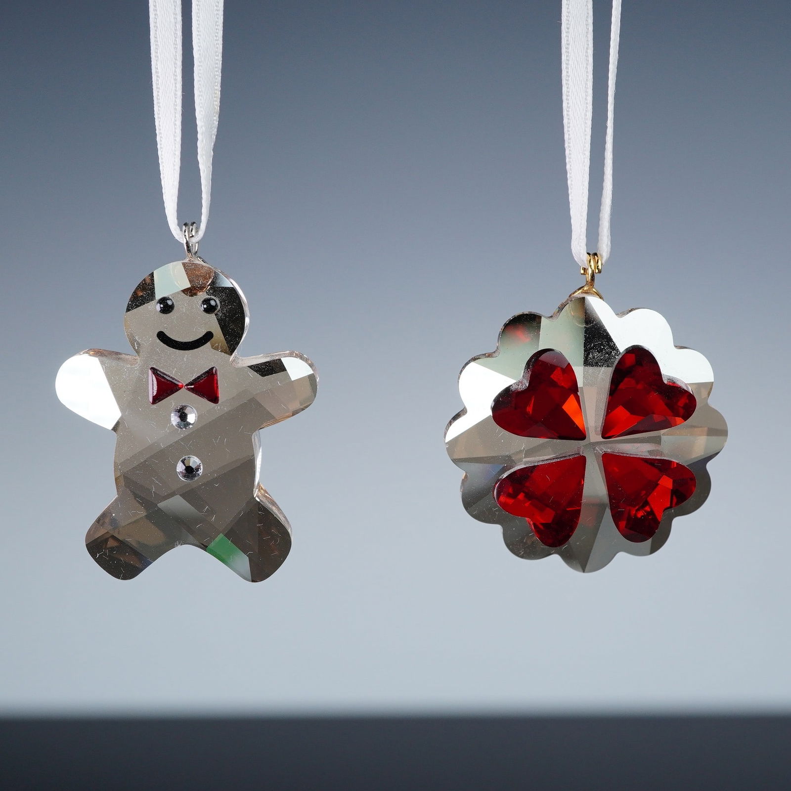 2pc Swarovski Crystal Christmas Ornaments: Pair of Swarovski crystal ornaments. Includes the Twinkling Gingerbread Man, number 1096031, crafted in clear faceted crystal with painted red bow tie, smiling face, and button details. Also features