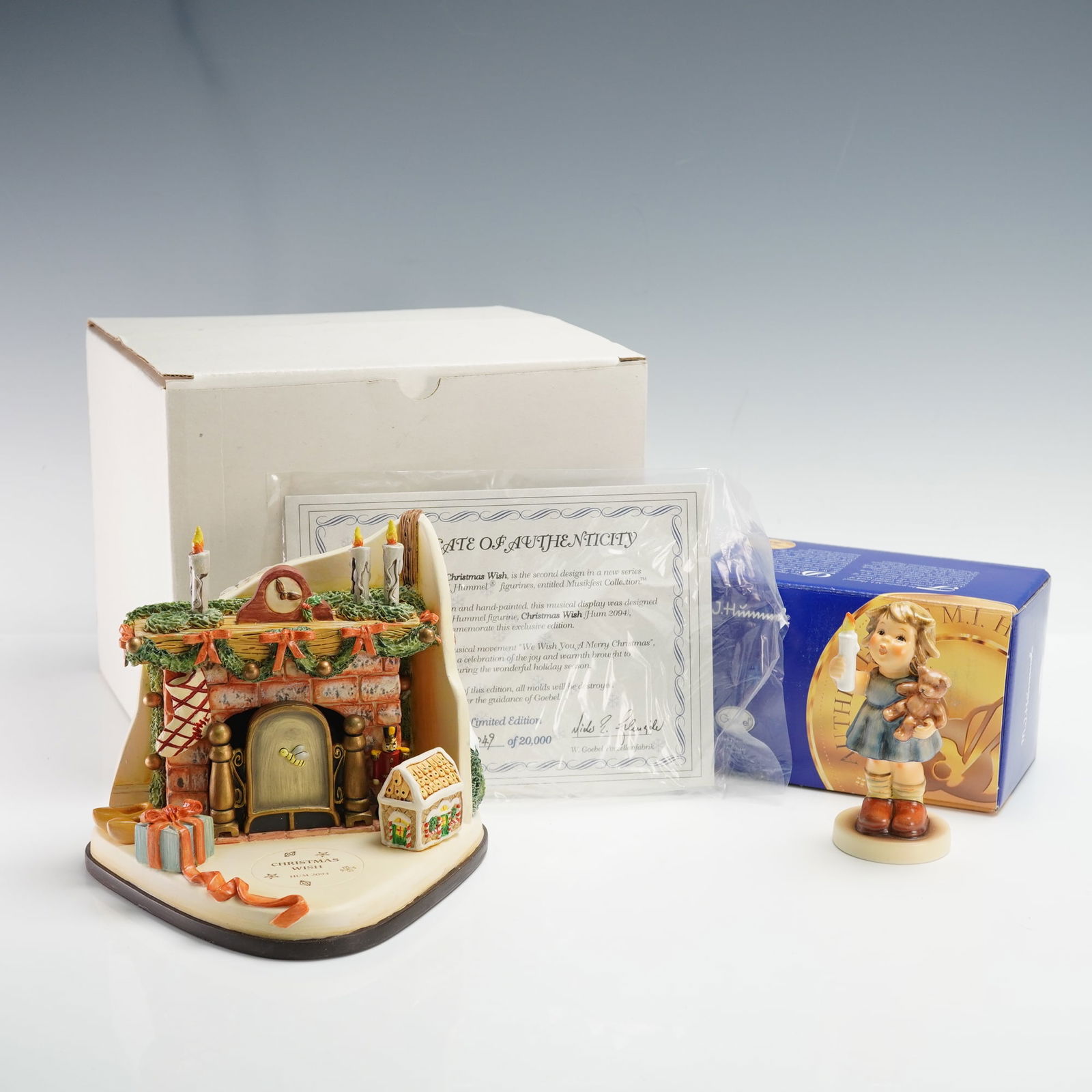 2pc Goebel Hummel Musikfest Music Box & Figurine, Christmas Wish: A charming two-piece porcelain ensemble from the Goebel M.I. Hummel Musikfest Collection titled "Christmas Wish," featuring a hand-painted figure of a young girl holding a candle and teddy bear beside