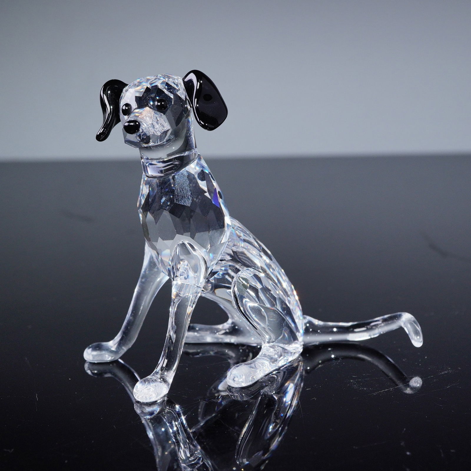 Swarovski Crystal Dalmatian Mother Figurine, Model No. 628948: A Swarovski crystal figurine titled 'Dalmatian Mother', model number 628948. Crafted from clear, colorless faceted crystal, depicting a seated dog. Distinct features such as the ears, nose, and specif