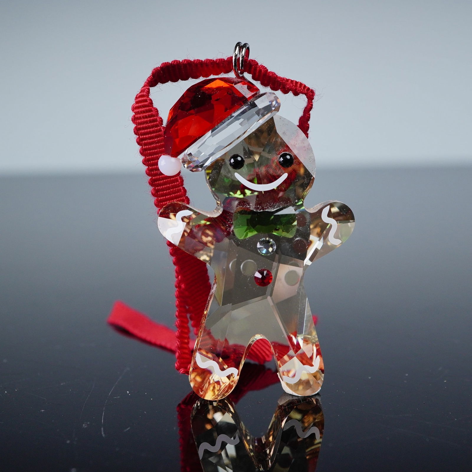 Swarovski Christmas Ornament, Gingerbread Boy: Swarovski crystal Christmas ornament Gingerbread Boy, item 5627607, featuring faceted golden crystal body with red Santa hat, green bow tie, and decorative crystal accents. Retains original Swarovski