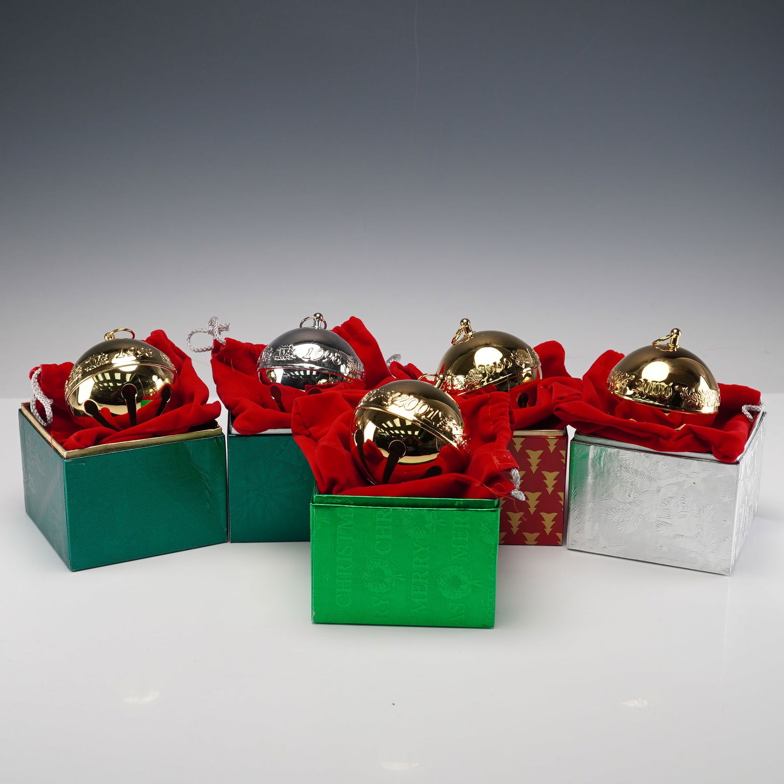 5pc Wallace Silversmiths Annual Sleigh Bell Ornaments: Set of five Wallace Silversmiths annual sleigh bells, each housed in its original presentation box with red fabric lining. Includes assorted years, featuring both gold- and silver-tone examples. Each