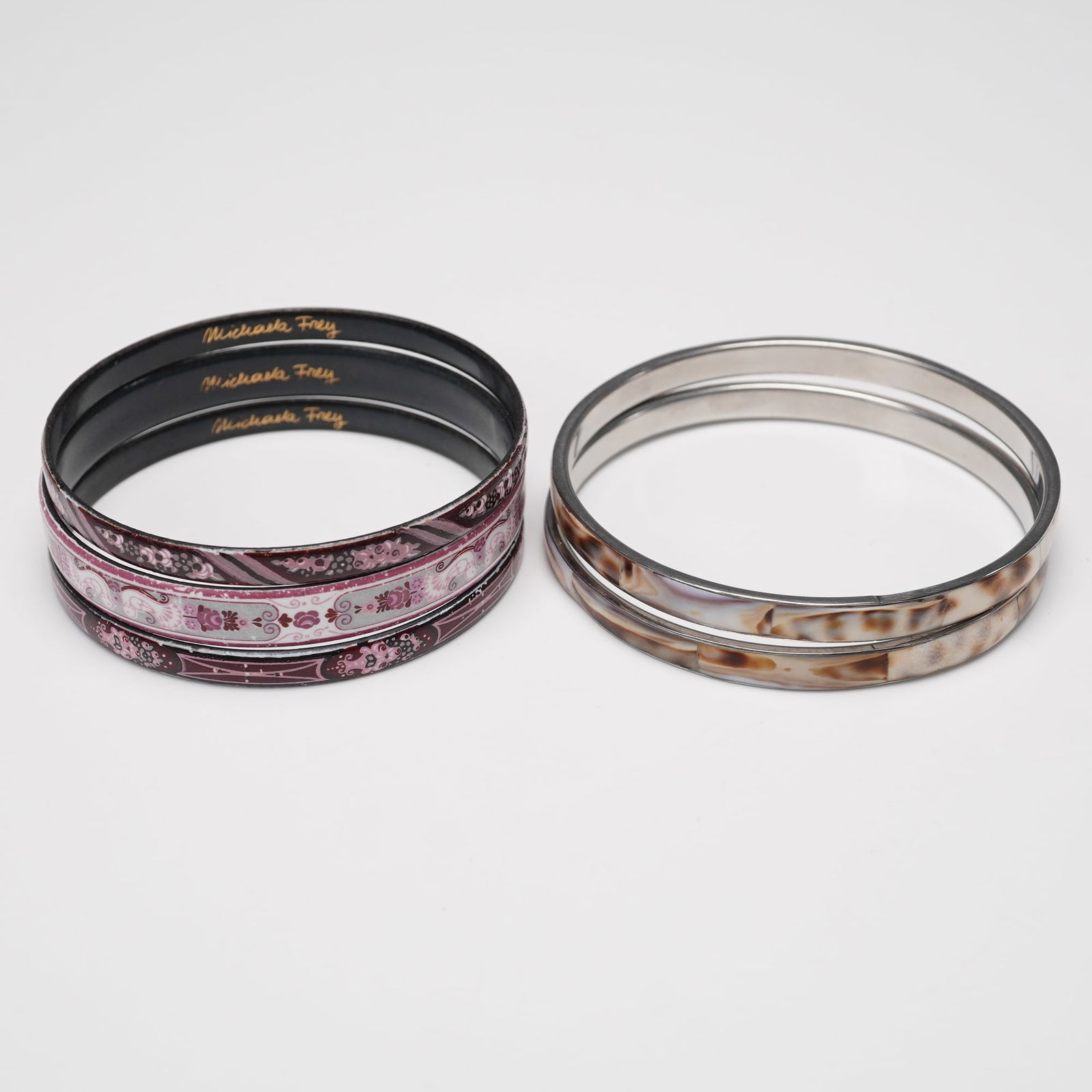 5pc Michaela Frey Pink Enamel and Brown Marbled Bangles: Group of five decorative bangles including three marked Michaela Frey with pink and burgundy enamel designs featuring floral and geometric patterns. Also included are two enamel bangles with marbled b