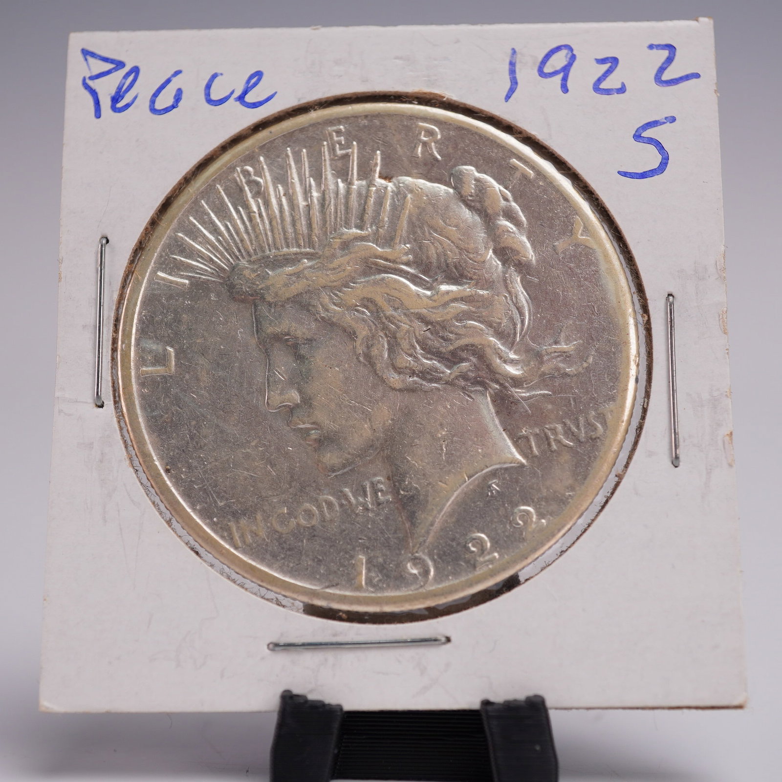 1922-S Peace Dollar Silver One Dollar Coin: This 1922-S Peace Dollar, minted at the San Francisco Mint struck from .999 silver. The obverse displays the dignified profile of Lady Liberty facing left, her hair softly flowing beneath a radiant cr