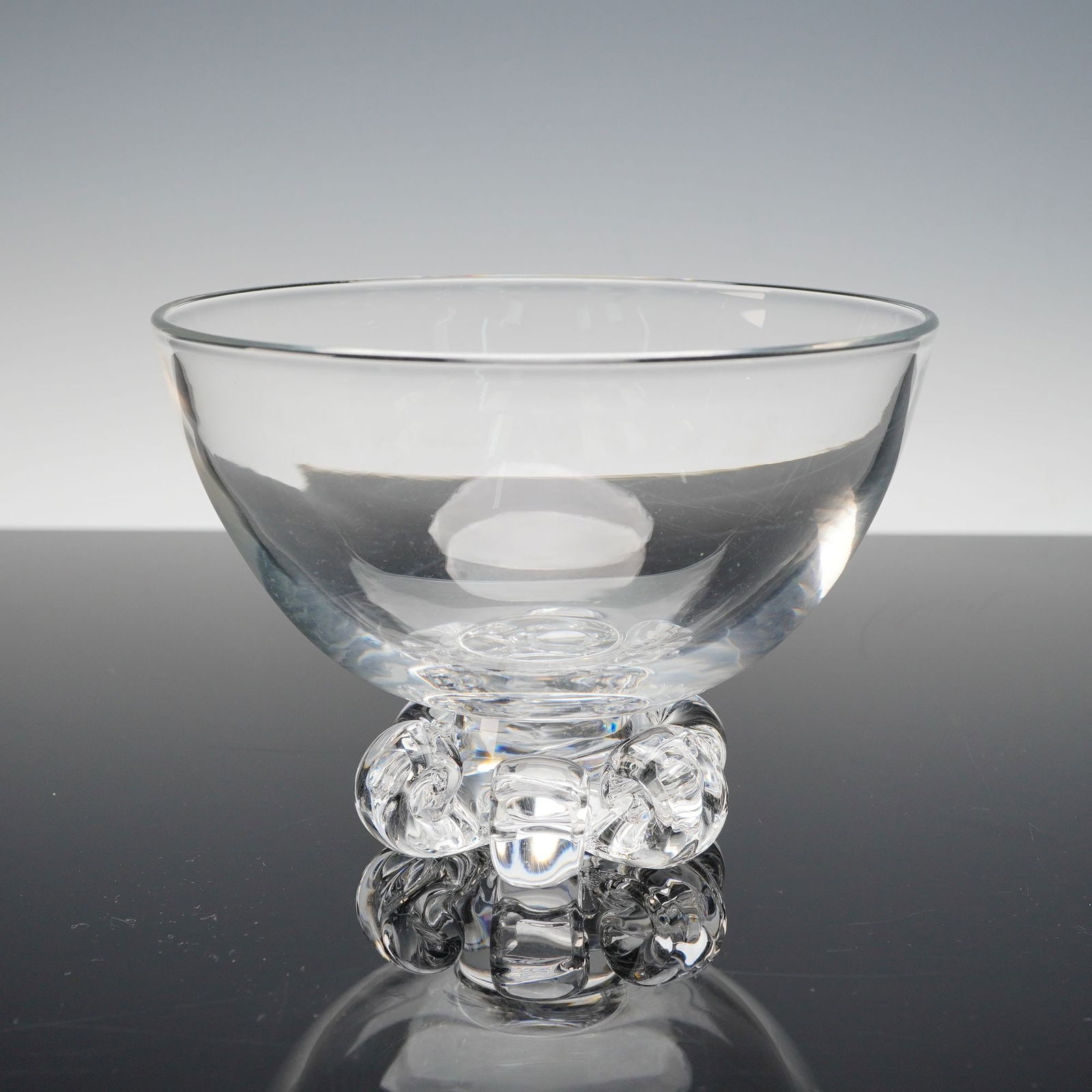 Steuben Crystal Footed Bowl with Six Lobed Feet: This elegant handblown crystal bowl by Steuben exhibits the impeccable clarity and craftsmanship for which the American glasshouse is renowned. Resting on six lobed, rounded feet that appear to bloom