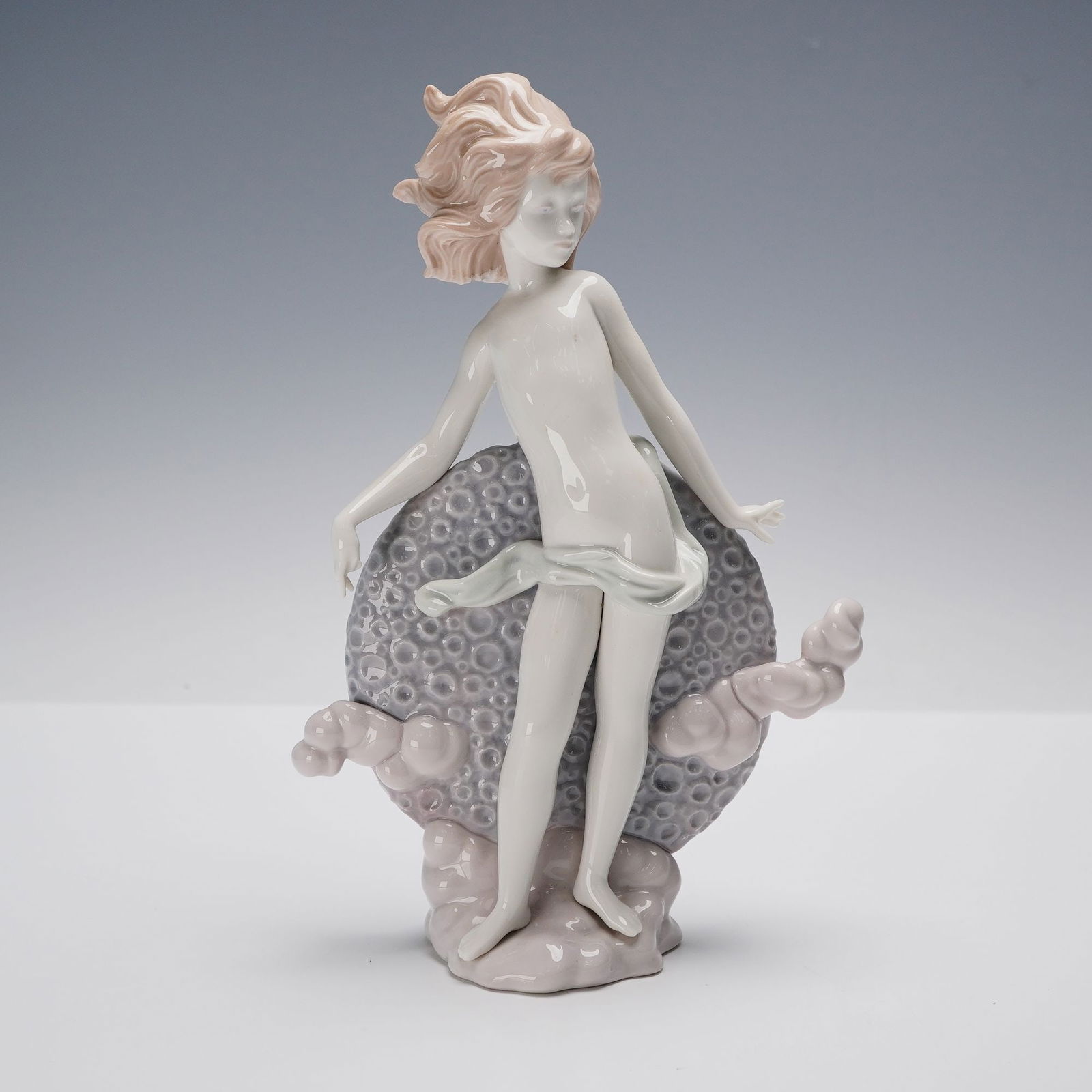 Lladro Porcelain Figurine Blue Moon 01001435: This Lladro porcelain figurine, titled Blue Moon, features a graceful, nude figure with flowing hair, standing on sculpted clouds. The delicate hand-painted details highlight the ethereal beauty of th
