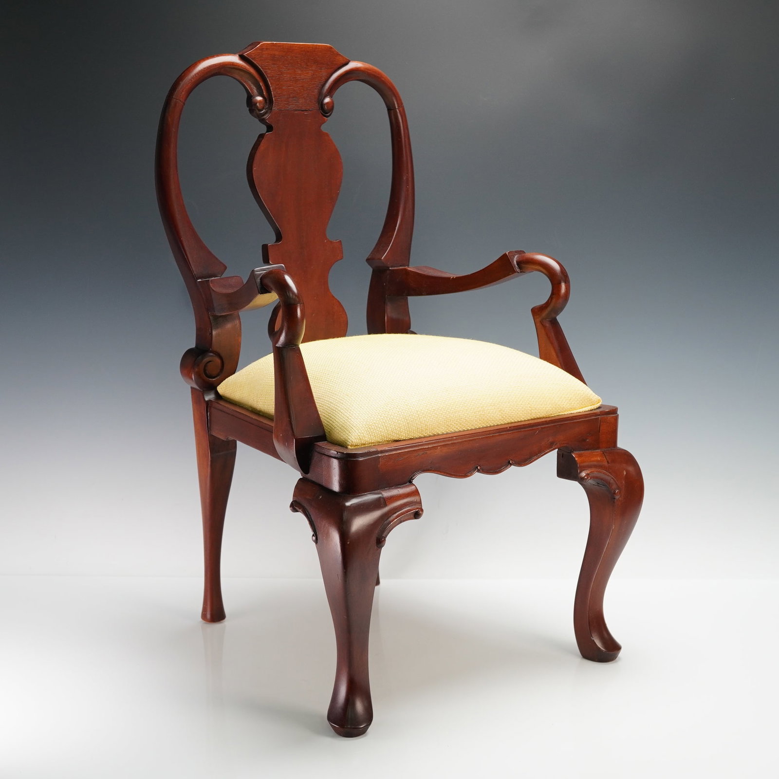Queen Anne Style Child's Mahogany Armchair with Upholstered Seat: A finely crafted child's armchair in the Queen Anne style, constructed of rich mahogany with a shaped splat back, scrolled arms, and cabriole legs terminating in pad feet. The seat features a yellow t