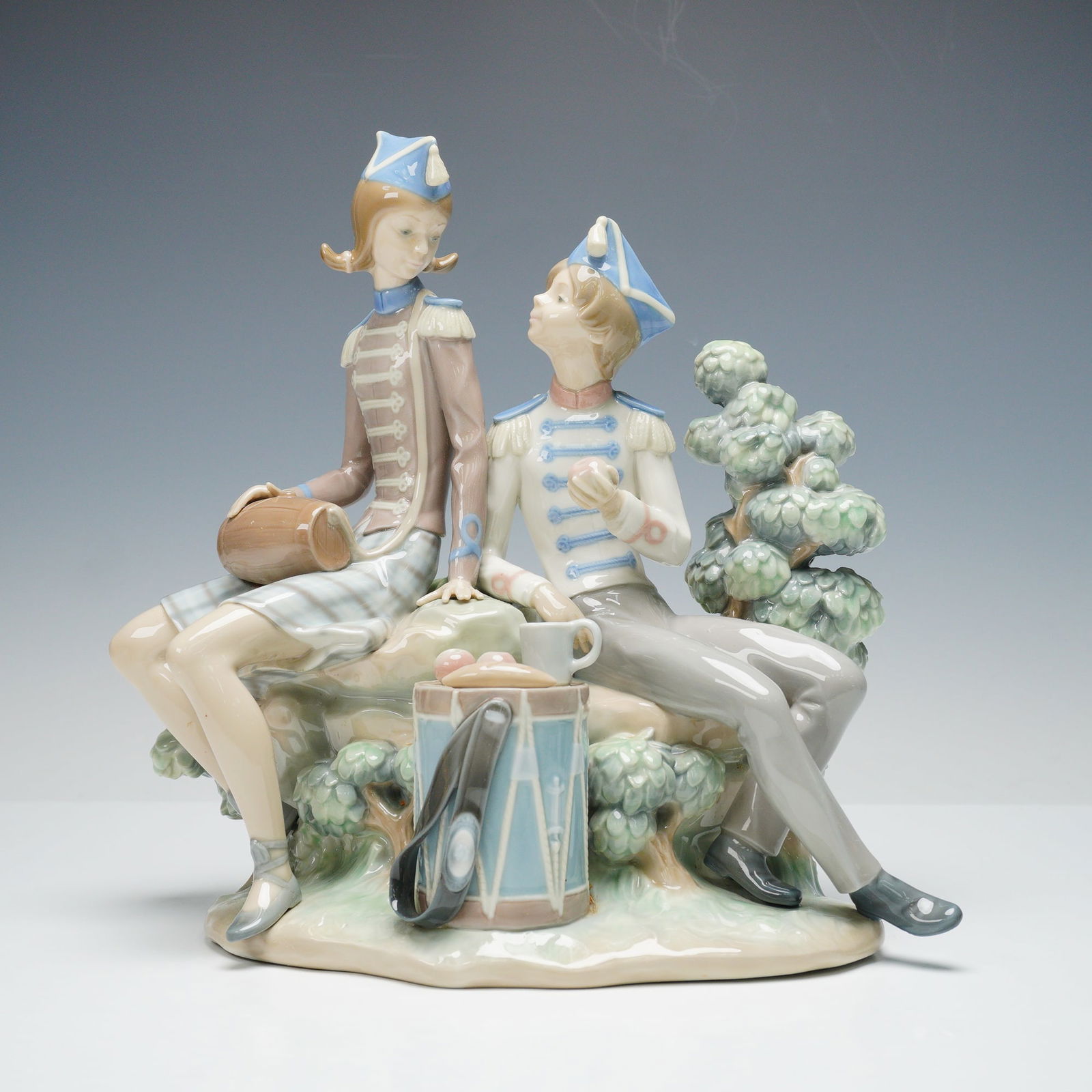 Lladro Porcelain Figurine, Vivandiere & Soldier 01001305: Charming Lladro porcelain figurine titled Vivandiere & Soldier (01001305), designed by Francisco Catala. This delicate composition depicts a young vivandiere and soldier seated together, sharing a lig