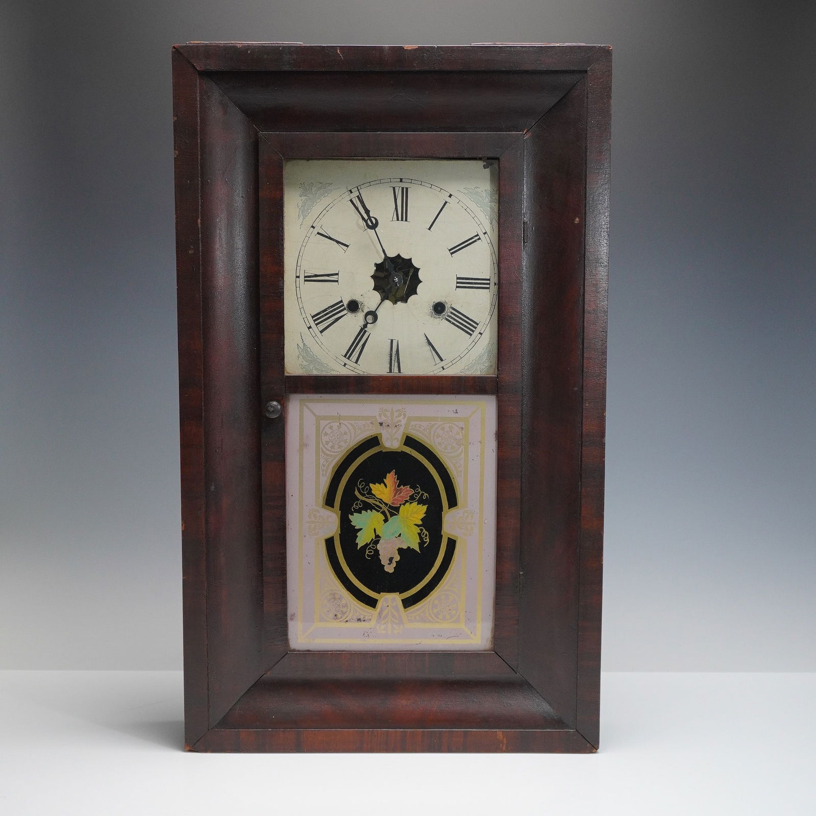 Jerome & Co. American Wall Clock, 19th Century: Antique Jerome & Co. American wall clock housed in a rectangular wooden case with a rich, dark finish. The upper section features a painted Roman numeral dial with a stenciled floral motif in the corn