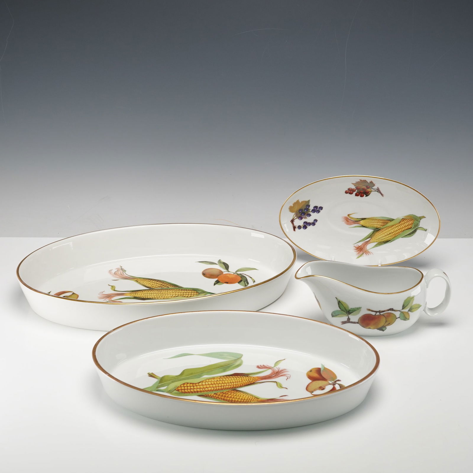 4pc Royal Worcester Porcelain Serve Ware, Evesham: Collection of porcelain serveware, featuring two oval casserole dishes, a gravy boat, and a matching underplate. Each piece is decorated with vivid fruit and vegetable motifs, including corn, peaches,