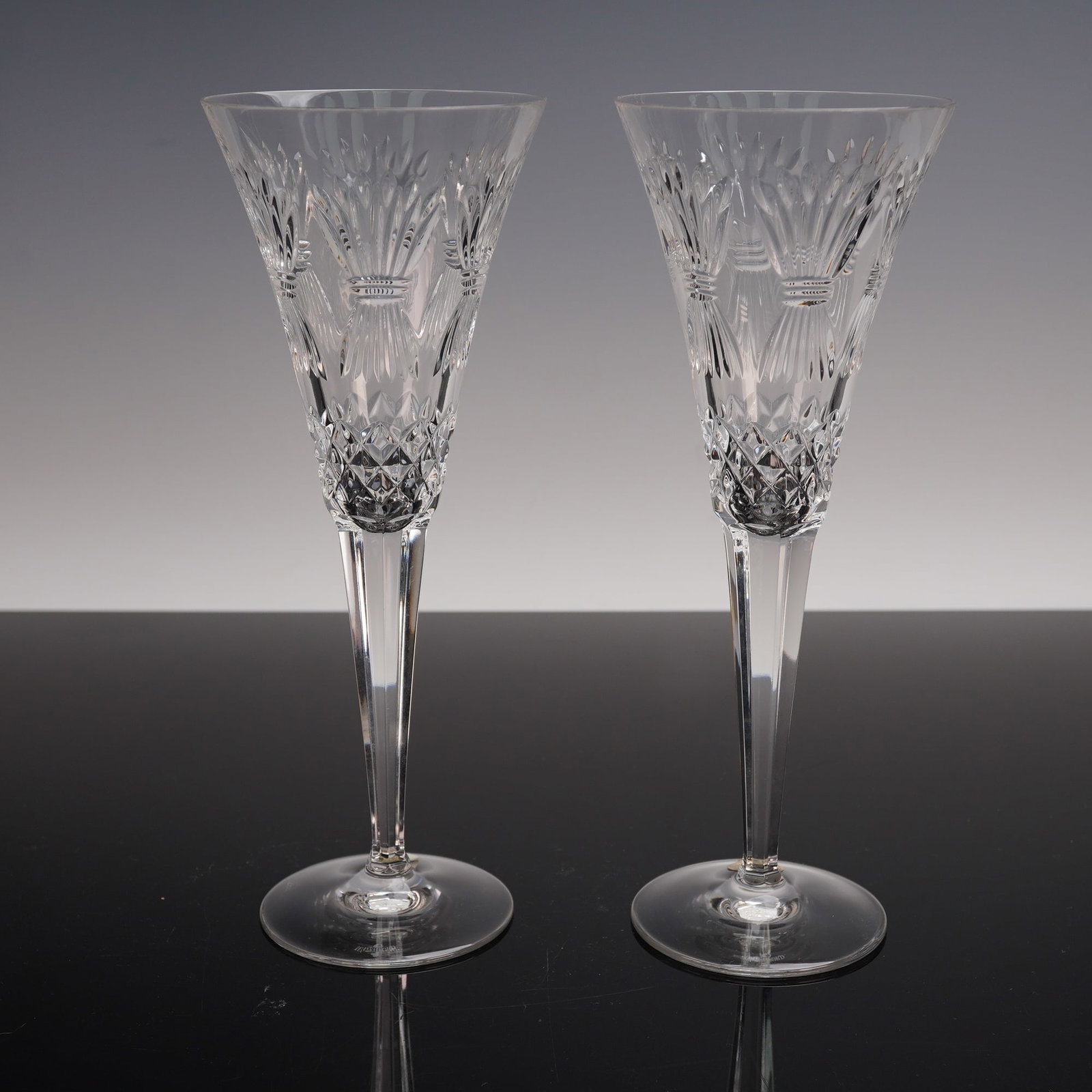 2pc Waterford Crystal Millennium Prosperity Champagne Flutes: A pair of Waterford Crystal Millennium Series Prosperity champagne flutes with tall slender stems and brilliant faceted bowls. The intricate cut patterns sparkle beautifully in the light making these 