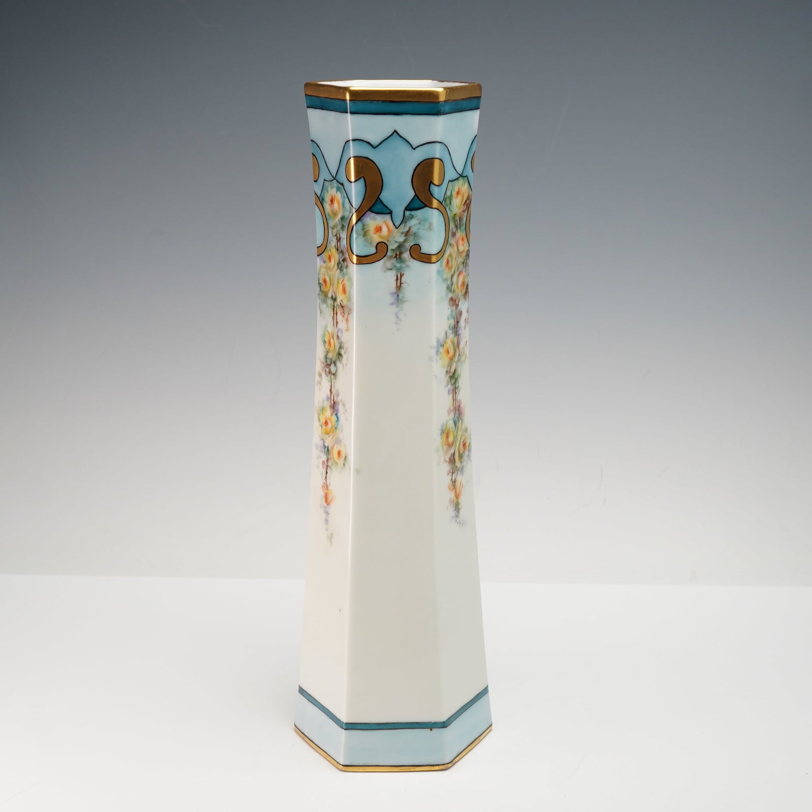 Austrian Handpainted Yellow Roses Hexagon Vase with Blue Trim: This exquisite Austrian vase features a hand-painted yellow rose motif, arranged along the sides of a stunning hexagonal design. The vase is accented with a delicate blue trim along the top and base, 