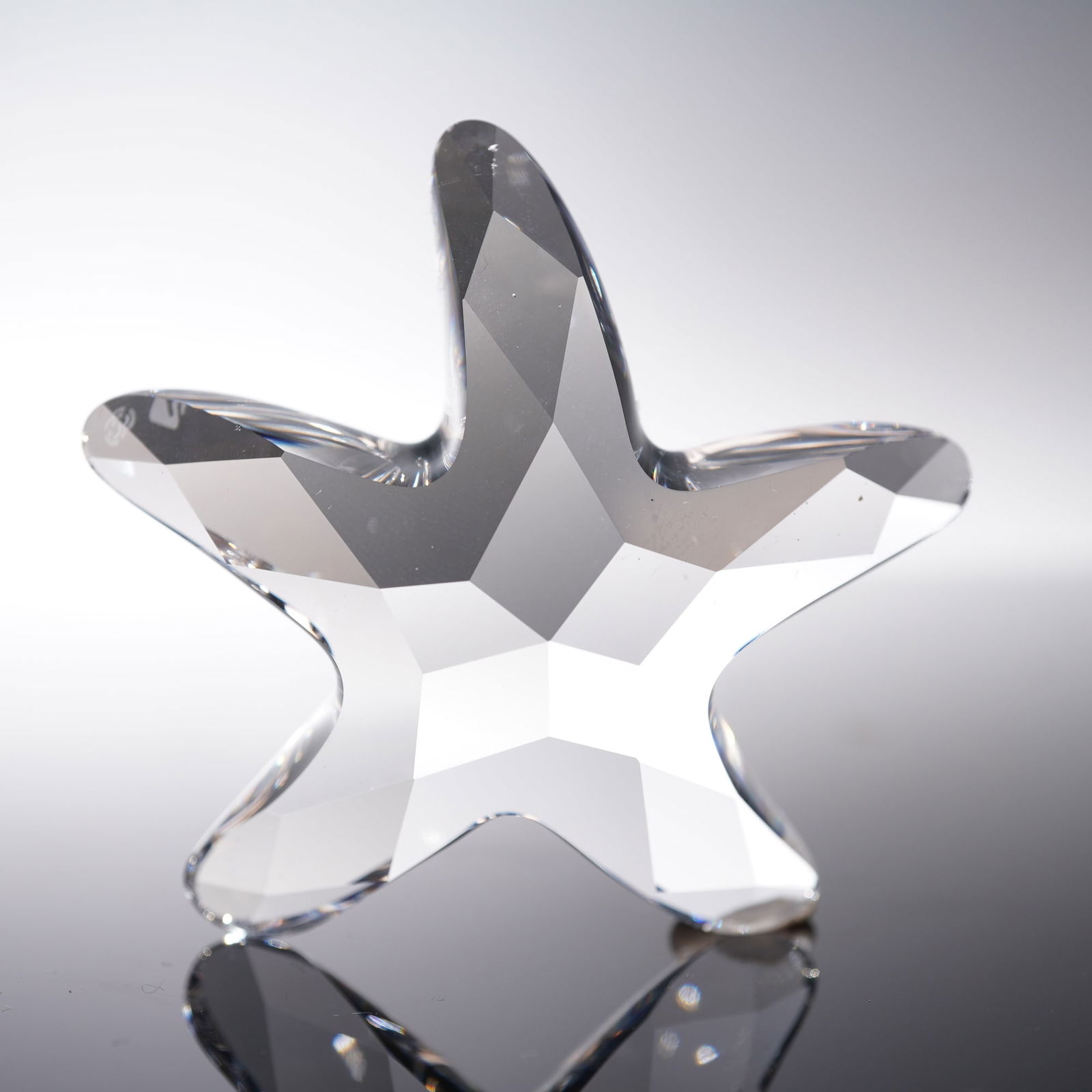 Swarovski Crystal Figurine, Starfish: A Swarovski crystal figurine depicting a beautifully faceted starfish, crafted in clear crystal with striking geometric cuts that capture and reflect light with brilliance. The piece bears the Swarovs