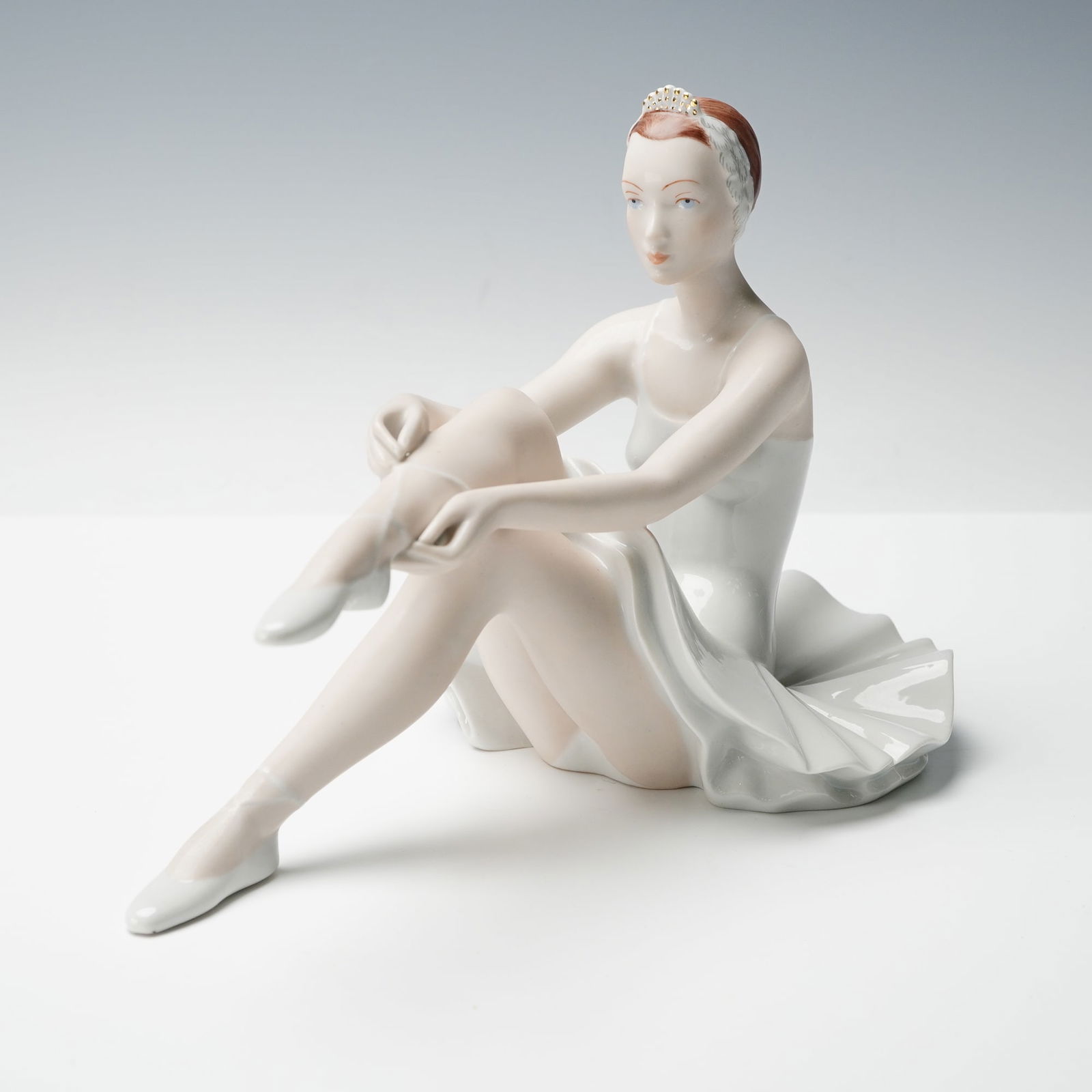 Royal Dux Porcelain Figurine, Ballerina: A finely modelled Royal Dux porcelain figurine depicting a seated ballerina adjusting her slipper, designed by V. Zakourel and marked with the familiar Royal Dux applied pink triangle and printed Czec
