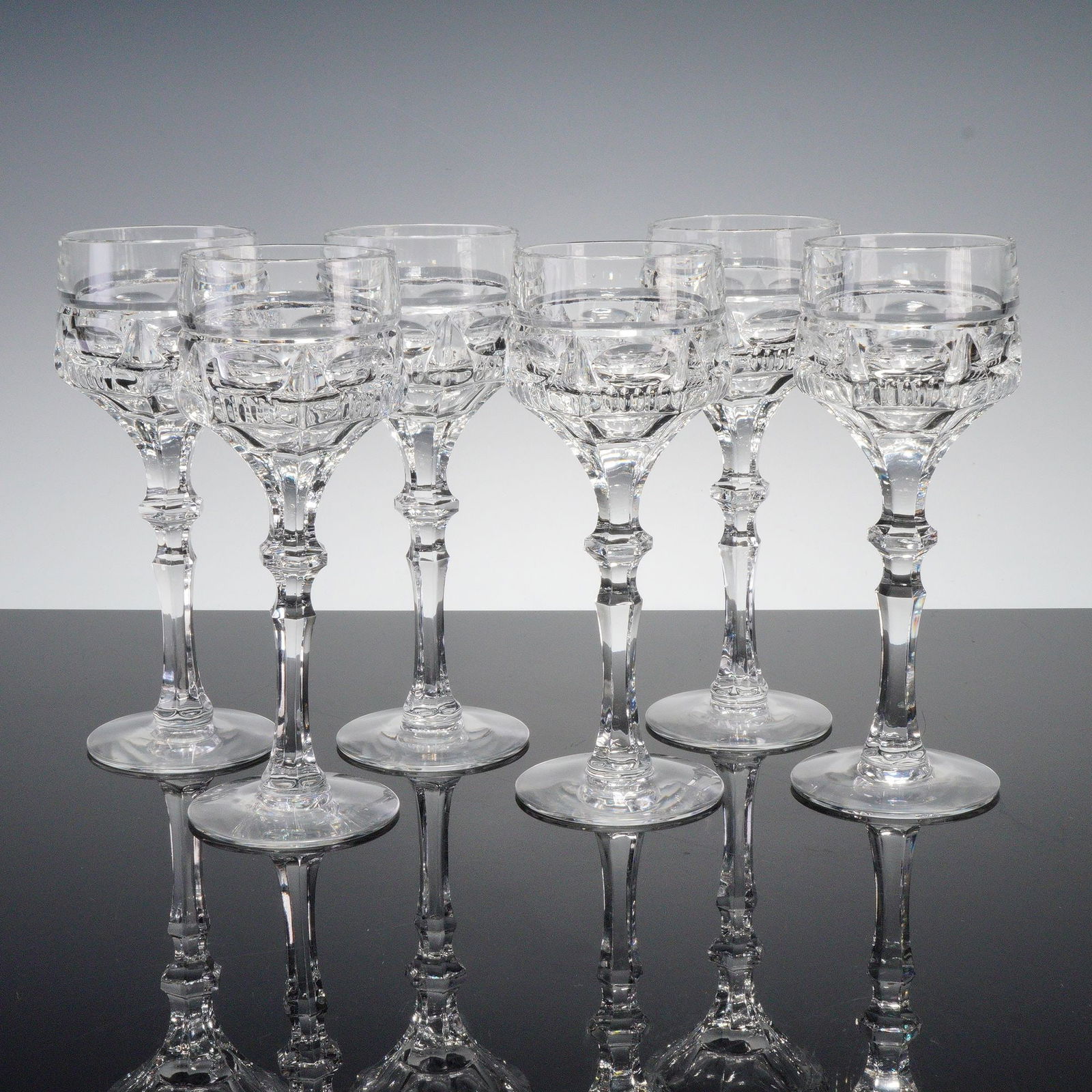 6pc Clear Cut Crystal Sherry Glasses: Set of six clear cut crystal sherry glasses featuring faceted stems and geometric banding with fine prism and fan detail. Elegant and finely crafted, displaying excellent clarity. Dimensions: 6.75"H x