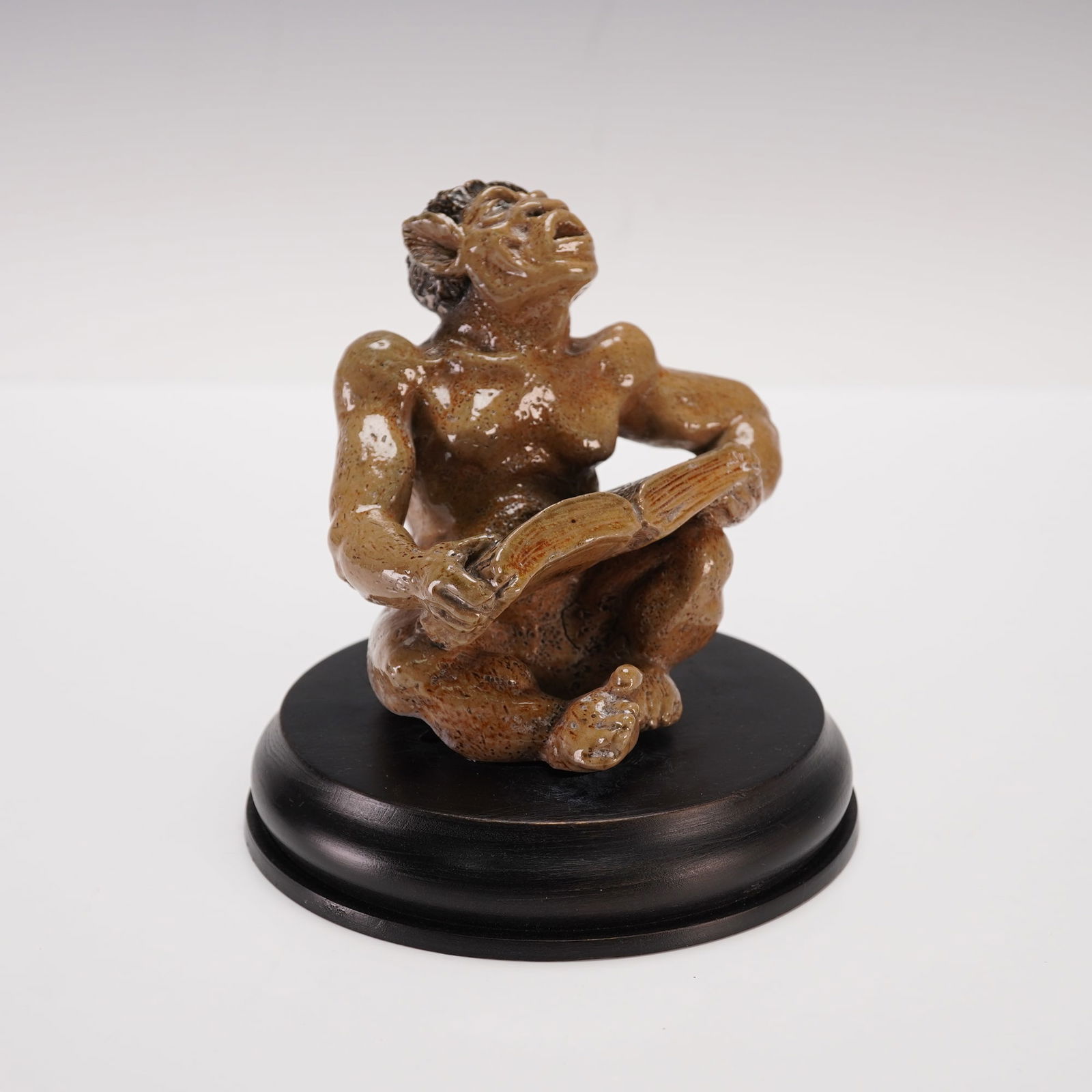 Martin Brothers Potters Stoneware Figurine, Imp Musician - The Singer: Glazed stoneware grotesque figure by the Martin Brothers depicting a seated imp or grotesque character holding an open music book and singing. The figure is modeled with pronounced features, including