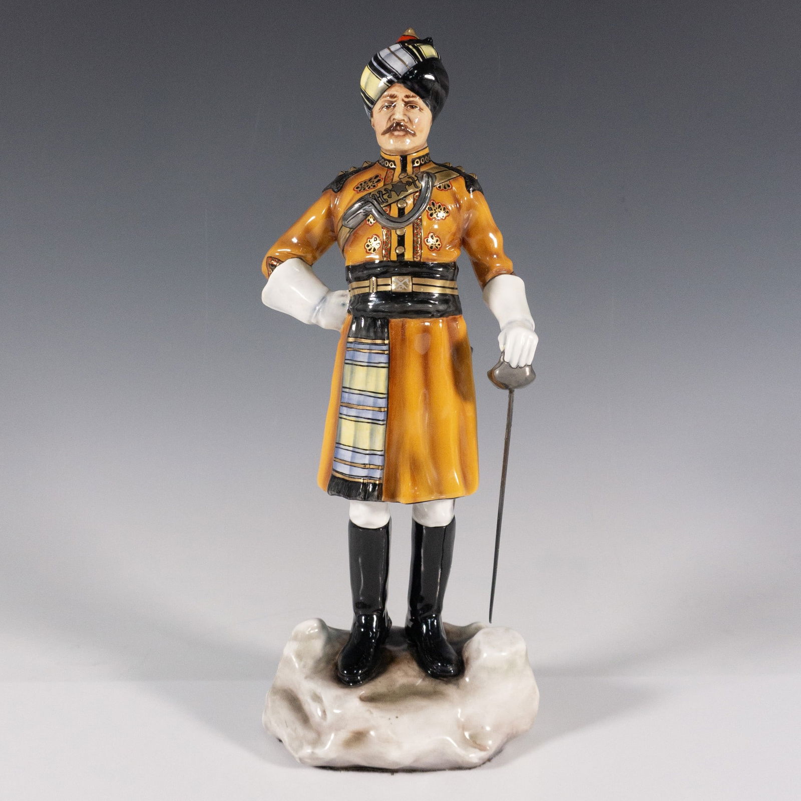 Michael Sutty Porcelain Figurine, Skinners Horse, 1920: Limited edition, 106 of 2000. Handmade and hand painted figure of an officer from the Indian Army holding a metal sword. Black and orange coloration. Michael Sutty backstamp. Artist: Michael Sutty Iss