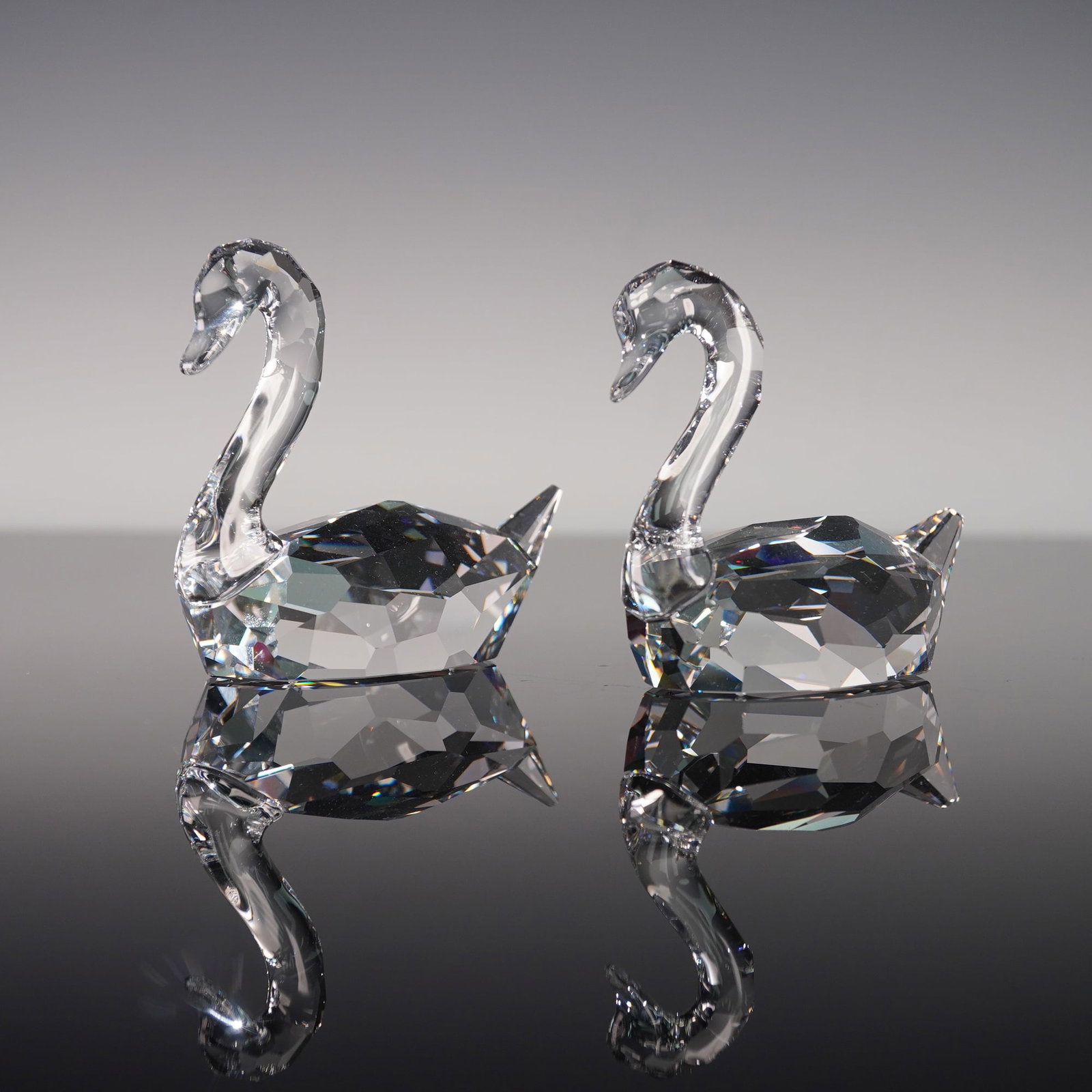 Swarovski Crystal Figurine, Swans Flirting: This pair of Swarovski crystal figurines, known as Swans Flirting and catalogued under number 837154, is crafted in clear faceted crystal. Each swan displays a smoothly sculpted neck and head above a