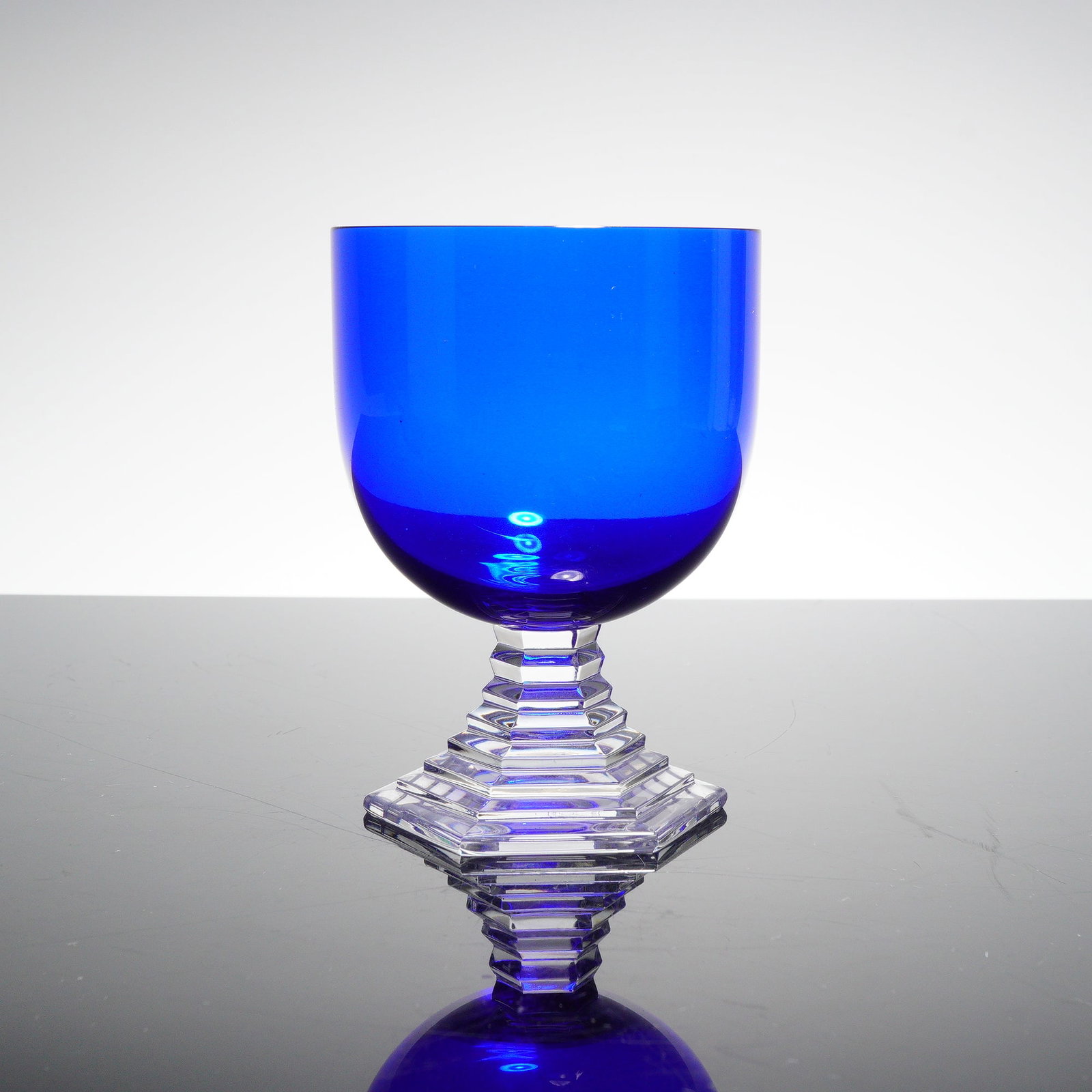 Baccarat Crystal Cobalt Blue Water Goblet, Orsay: This example from the Orsay line features a deep cobalt blue bowl set above a sharply faceted clear stem, executed in Baccarat crystal with the pattern's distinctive stepped geometric form. The unders
